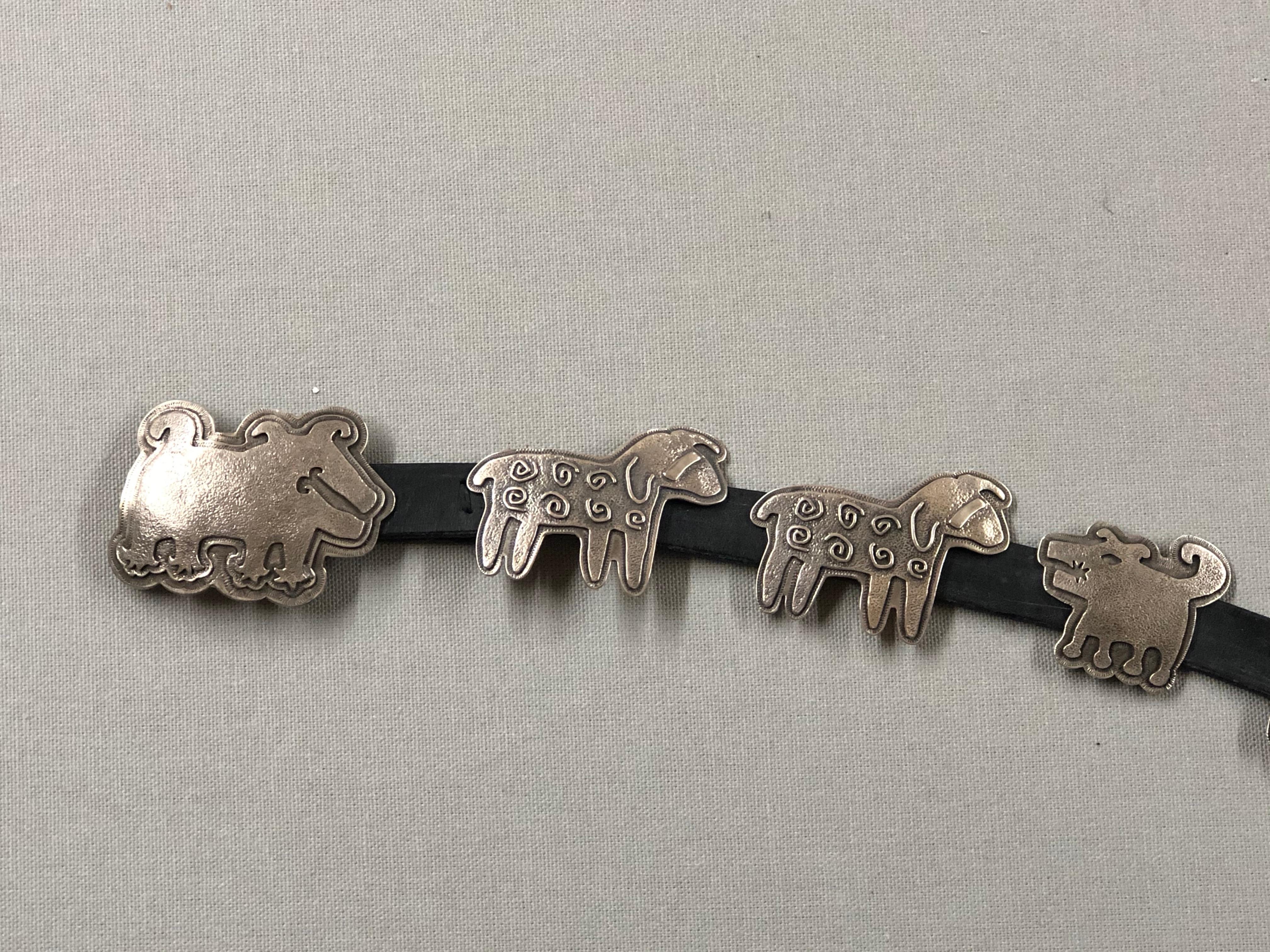 Wide Ruins Gang Concho Belt designed by Melanie Yazzie, cast sterling silver dogs, ram and sheep and leather strap. The strap is not punched. Customers' measurements need to be provided for proper sizing. 

Melanie A. Yazzie (Navajo-Diné) is a