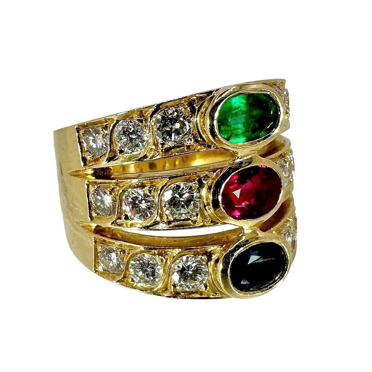 An 18K yellow gold ring with a design area measuring 3/4 of an inch, and set with an oval cut emerald, ruby, and sapphire. To the left and right of each beautiful colored gem are 3 pave set diamonds. The 18 diamonds weigh approximately 2.5ct total