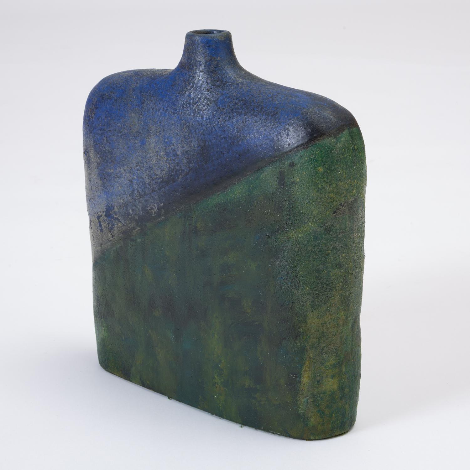 A wide-hipped vase with a narrow opening, this stylized shape was produced by Italian sculptor and ceramicist Marcello Fantoni for Raymor. The vase is hand painted, and the glaze has notes of teal, midnight, ultramarine and jade. Signed on