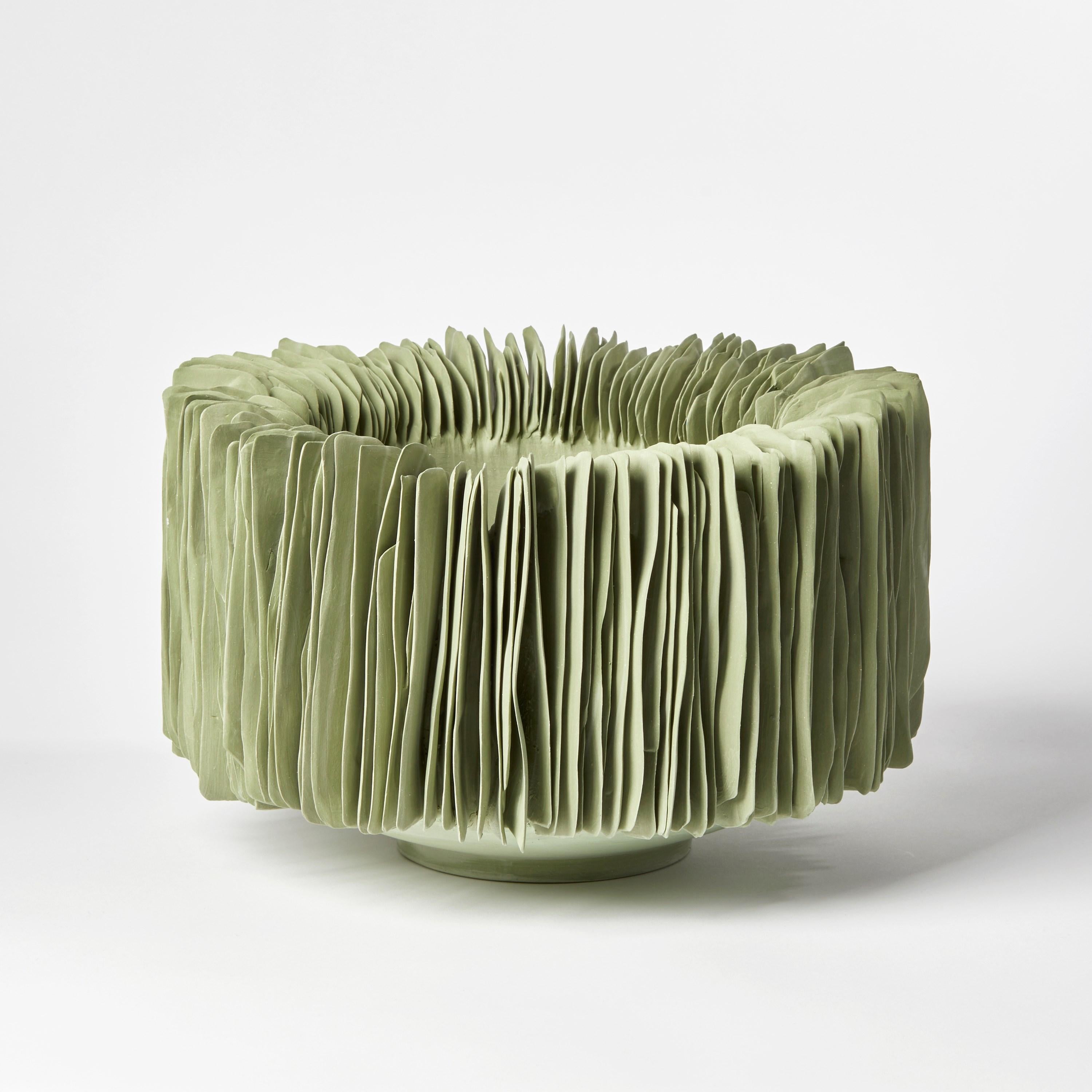 'Wide vertical bowl in olive green' is a unique porcelain sculptural bowl by the British artist, Olivia Walker.

Walker works in porcelain to create pieces that explore ideas of growth and decay through the construction and layering of complex