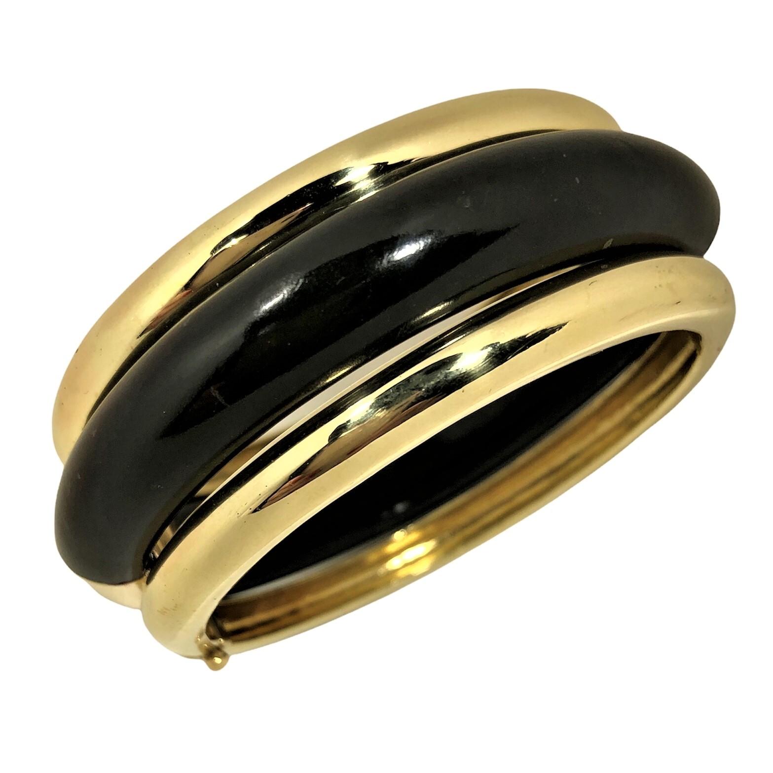 This simple yet powerful 18k bangle bracelet is designed as three concentric bands, those being one black jade section bracketed by 18k yellow gold somewhat narrower bands. The total width is approximately one inch. Everything about it speaks of the