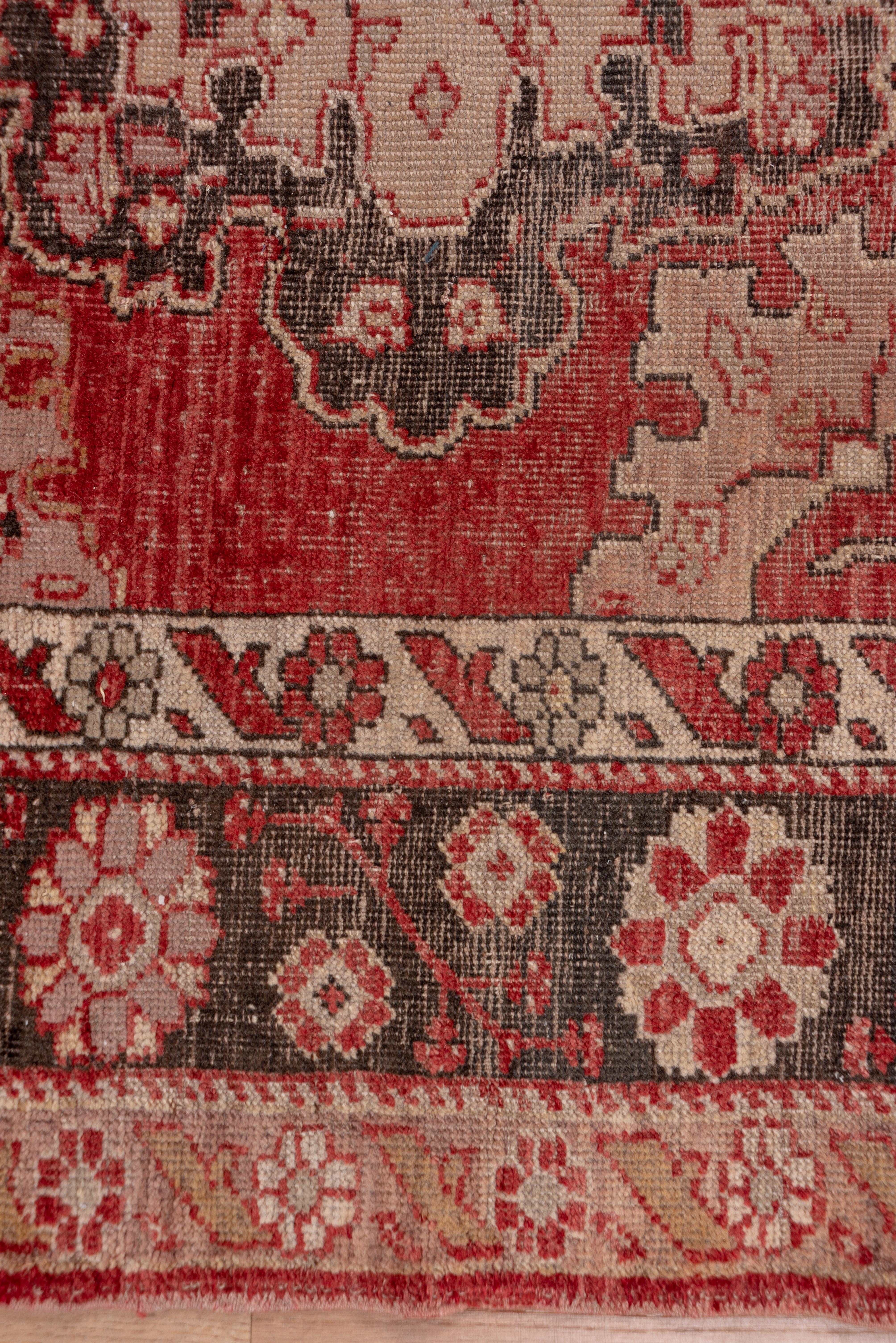 This wide west Anatolian runner displays ten scalloped octofoil medallions in pale green, dark brown and beige on a rather worn abrashed red ground with half side medallions and a strongly abrashed main border with rosettes and hyacinth sprays an