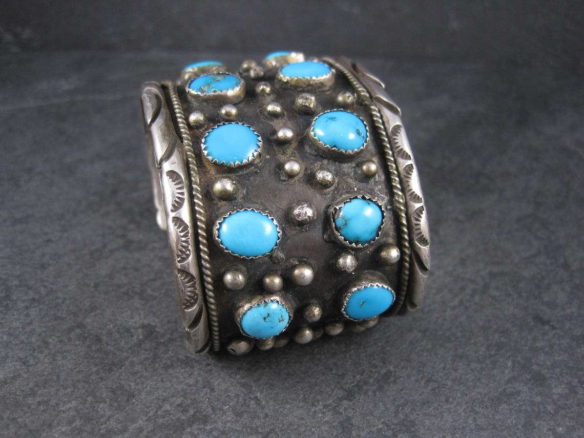 This gorgeous vintage Native American cuff bracelet is sterling silver.
It features 14 turquoise gemstones, likely from the Bisbee mine.

This bracelet measures 1 13/16 inches wide.
It has an inner circumference of 6 1/2 inches, including the 1 1/4