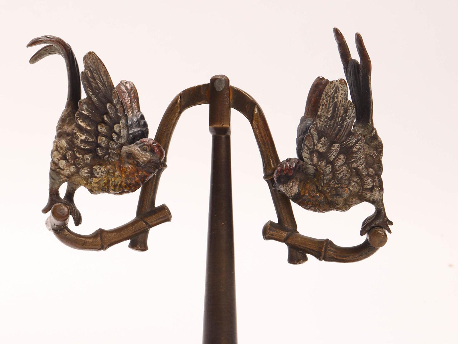 Wiener bronze swing with two parrots on a circular base. The parrots are painted in different colors. Reciprocating mechanism. Wien Austria 1890 ca.