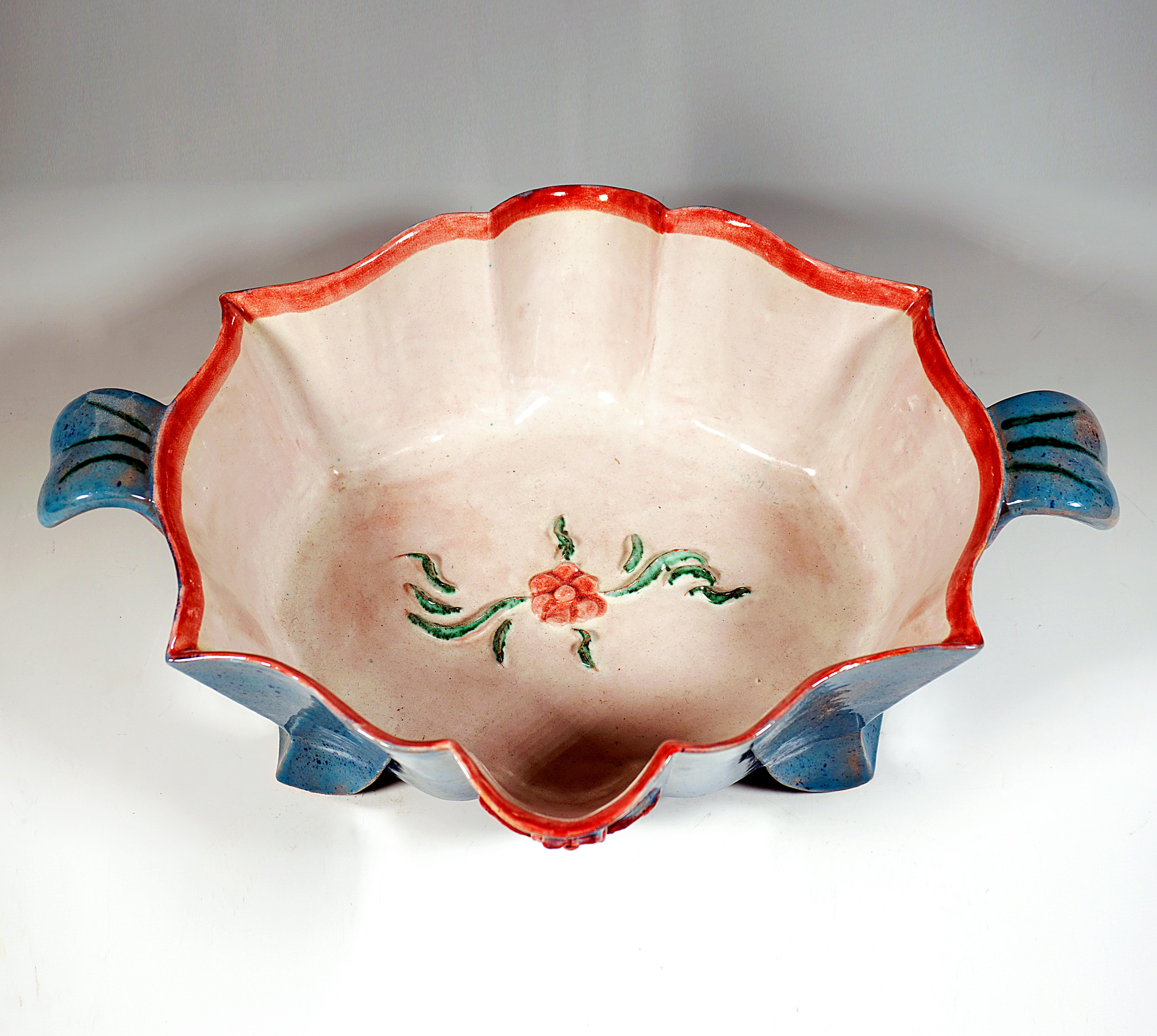 Large bowl on an oval ground plan with flared, wavy and curved walls on four swept-out feet in the shape of leaves, flower and leaf decoration in relief on the bowl base and on the outside, colored glazed in an expressive manner.

Manufactory: