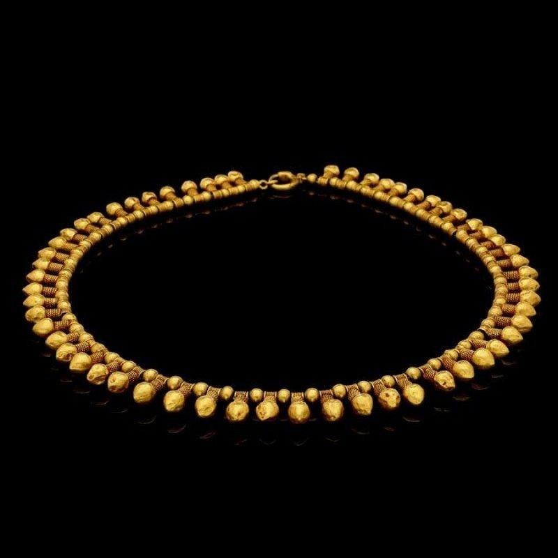 A French gold necklace by Wièse c.1890, designed in the archaeological revivalist style, the fringe-style necklace strung with alternate polished spherical beads and phallic motifs with rope twist and hammered decoration, all to a clasp designed as