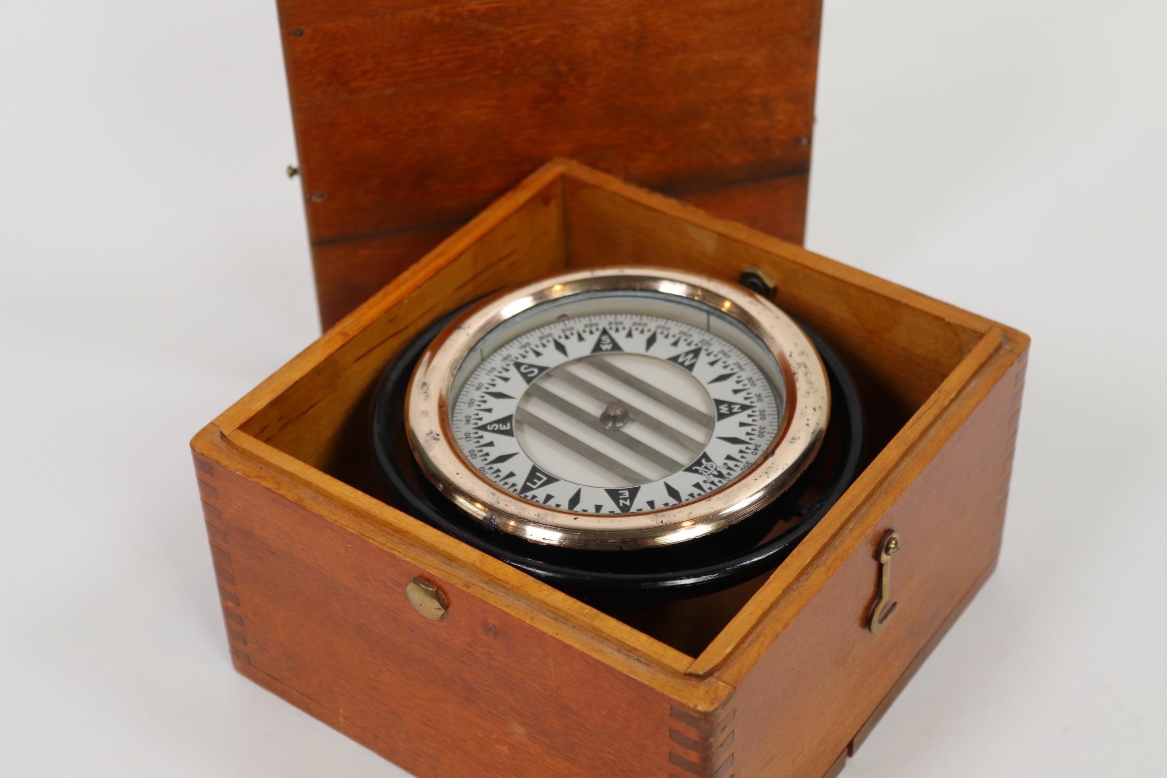 Brass boat compass by Wilcox Crittenden set into a dovetailed box with lid. Polished brass compass bezel. Dated February 24, 1953. Weight is 7 pounds.