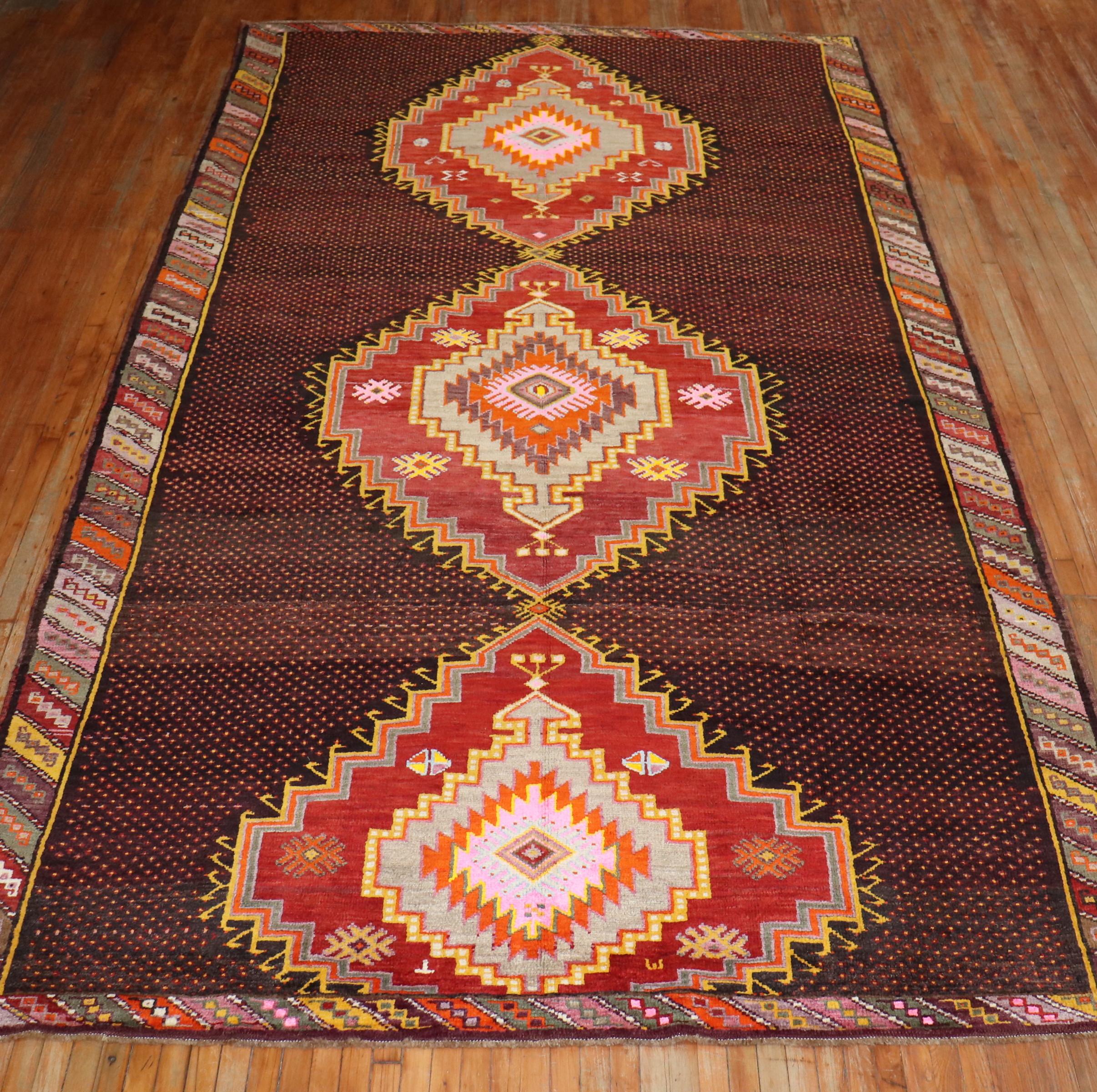 One of a kind corridor size Turkish Kars rug from the 20th century. A dark brown geometric field with saturated colors in brown, pink red, coral, orange mustard and green.

Measures: 8'8