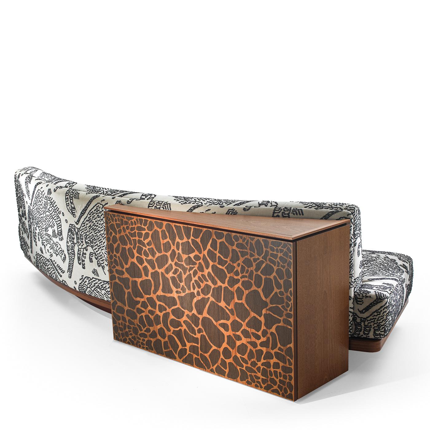 A striking multifunctional design, this sofa is distinguished by a back cabinet with two doors, enriched with a giraffe-striped inlay work on the mahogany plywood structure. Upholstered with a tiger mountain fabric, it boasts a slightly curved and