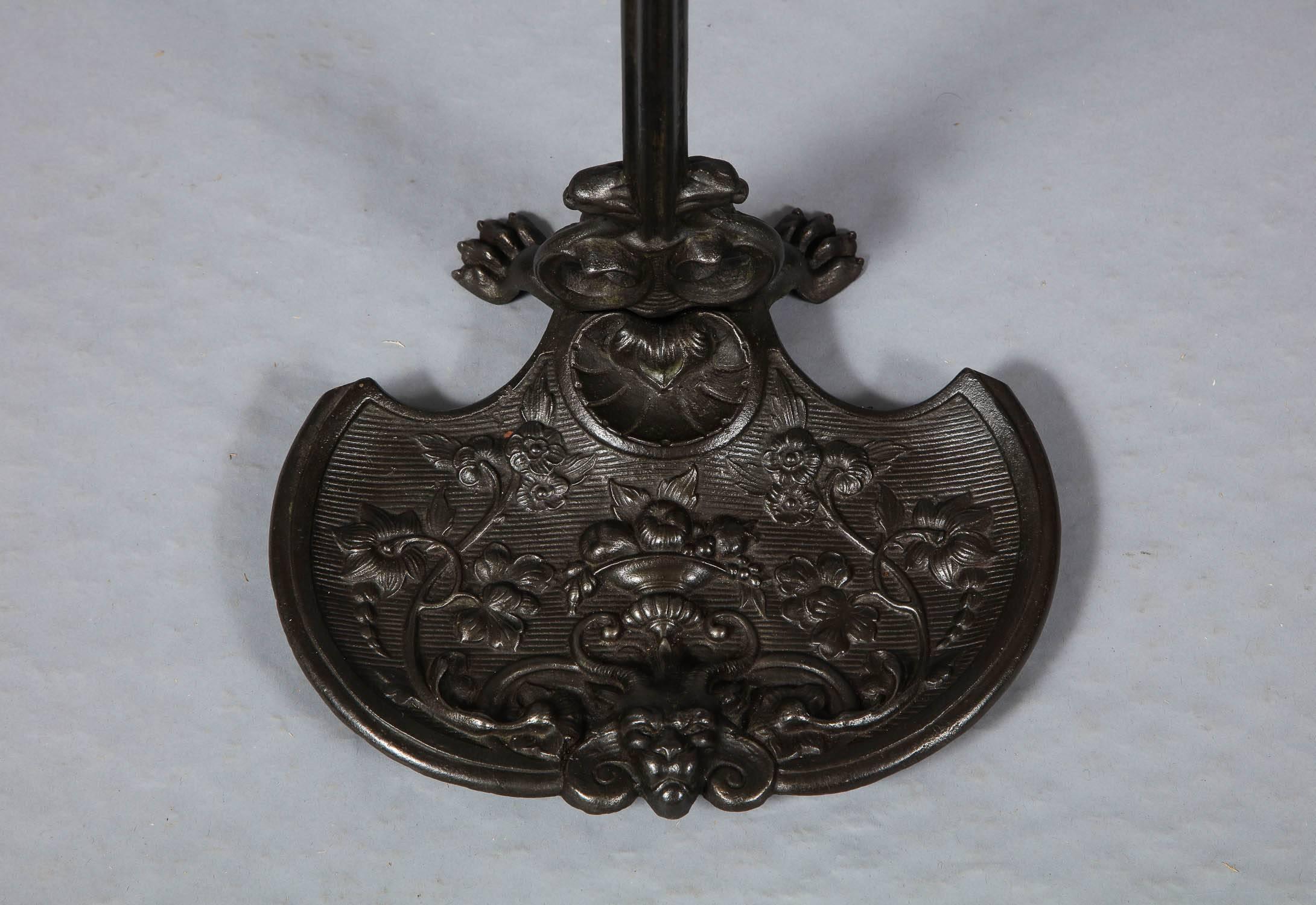 Fine English mid-19th century cast iron umbrella, walking stick or fire tool stand in richly detailed and patinated cast iron, the finial depicting the head of a wild cat, the foliate decorated arms over molded shaft, over base cast with trailing