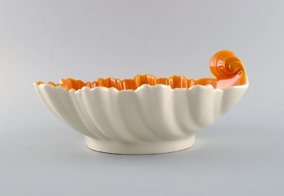 Wilhelm Kåge (1889-1960) for Gustavsberg. 
Hand-painted faience bowl shaped like a seashell. 1920s / 30s.
Measures: 24 x 11 cm.
In excellent condition.
Stamped.