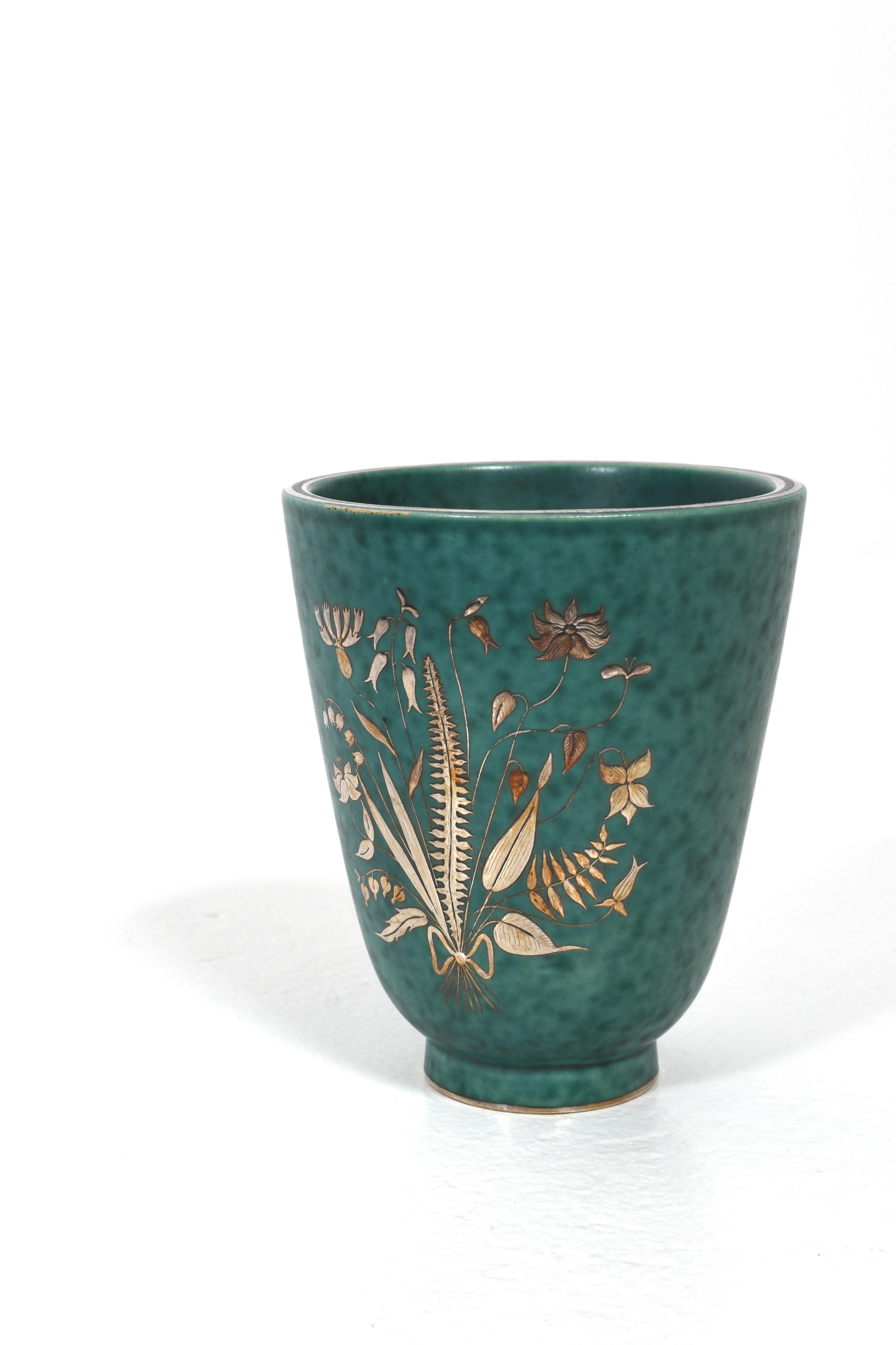 Vaso di Wilhelm Kåge ARGENTA per Gustavsberg, prodotto in Svezia negli anni '40. Questo vaso vintage in ceramica presenta uno smalto verde intenso e un elegante disegno floreale intarsiato in argento. Un bell'esempio di design moderno scandinavo,