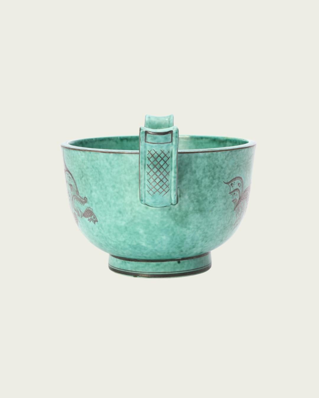 1960s, Sweden. Art deco footed bowl by famed Swedish Ceramicist and designer Wilhelm Kåge from his Argenta collection of stoneware produced for the Gustavsberg Factory. Speckled turquoise glaze with silver leaf details illustrating a sea creature