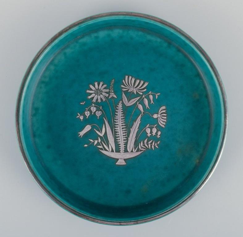 Wilhelm Kåge (1889-1960) for Gustavsberg, Sweden.
Low Art Deco ceramic bowl with silver decoration featuring a floral motif. 
From the 