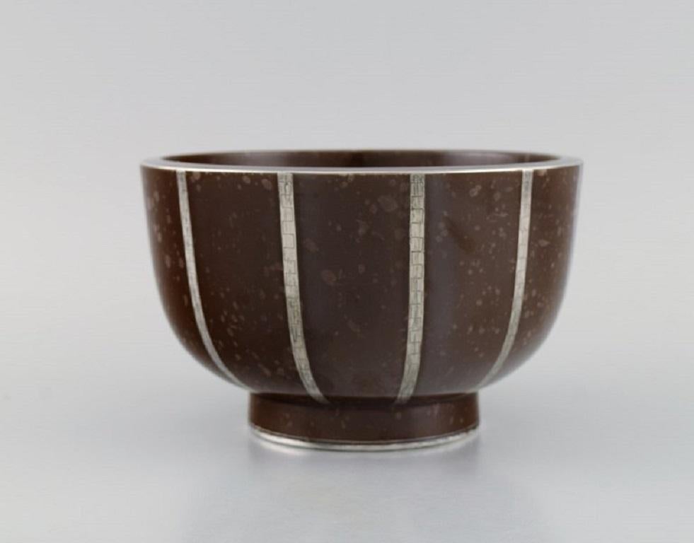 Wilhelm Kåge for Gustavsberg. Rare Argenta Art Deco bowl in glazed ceramics with silver inlay. 
Beautiful speckled glaze in brown shades. 1940s.
Measures: 17 x 10.5 cm.
In excellent condition.
Stamped.