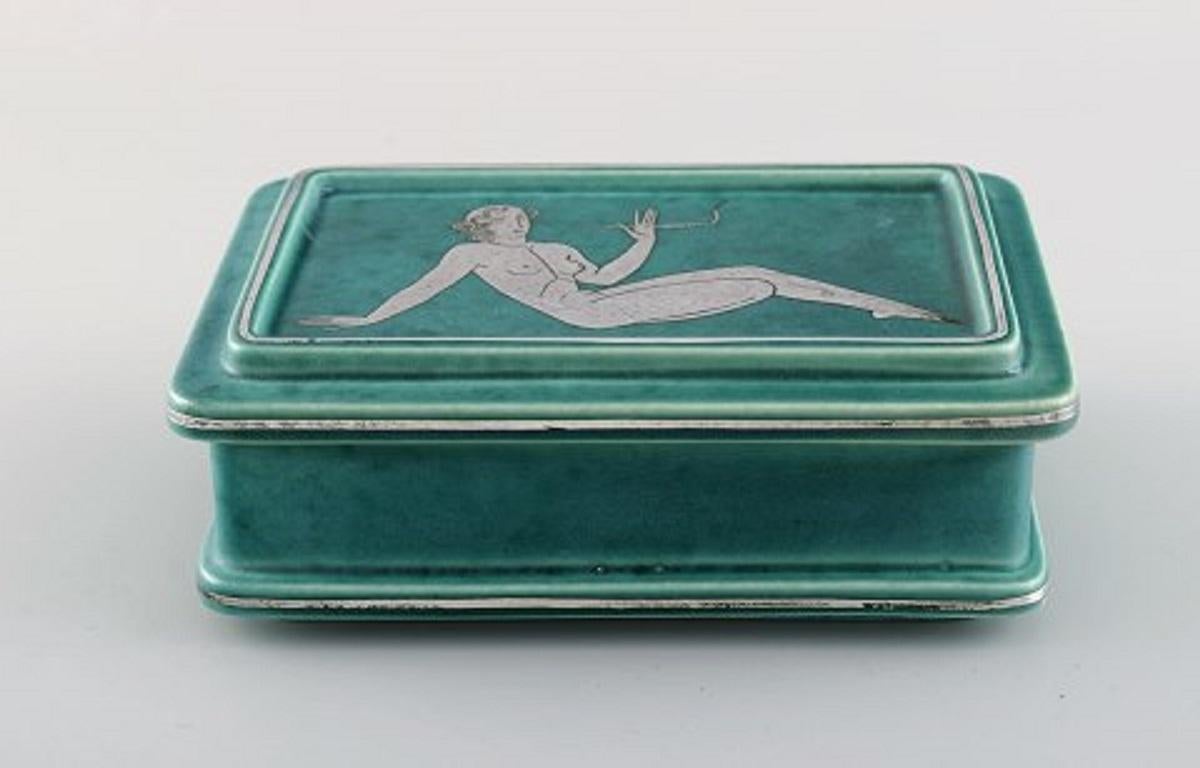 Wilhelm Kåge for Gustavsberg. Rare Argenta Art Deco lidded box in glazed ceramics decorated with a naked woman in silver inlay.
Sweden, 1940s.
Measures: 15 x 10 x 5.5 cm.
In excellent condition.
Stamped.