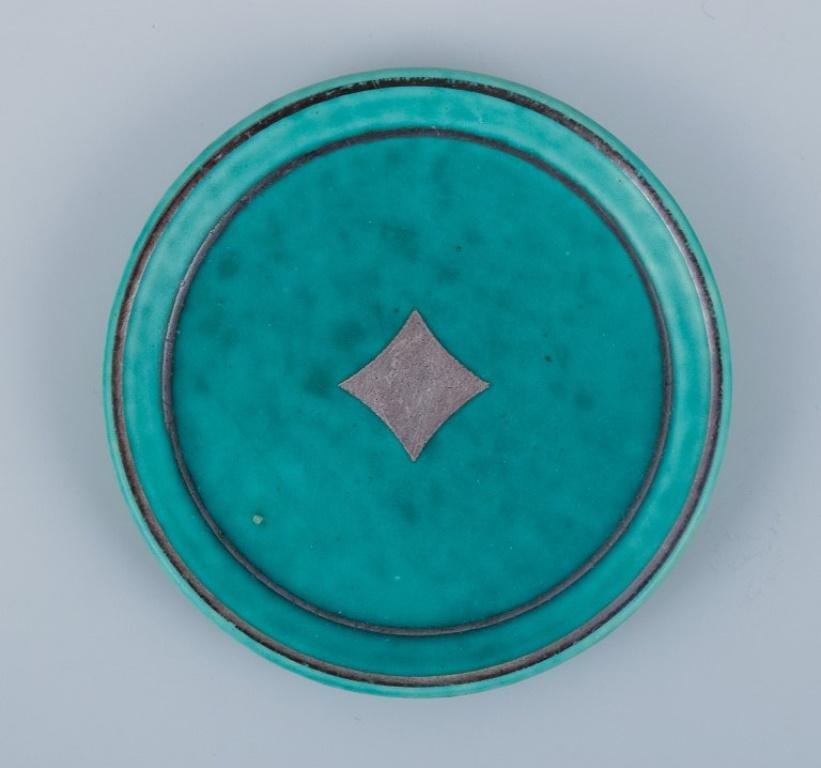 Wilhelm Kåge for Gustavsberg.
A set of five Argenta ceramic bottle coasters with silver inlaid designs.
Decorated with card suits.
From the 1940s.
Model number 924.
Marked.
In excellent condition.
Dimensions: D 9.2 cm x H 1.0 cm.