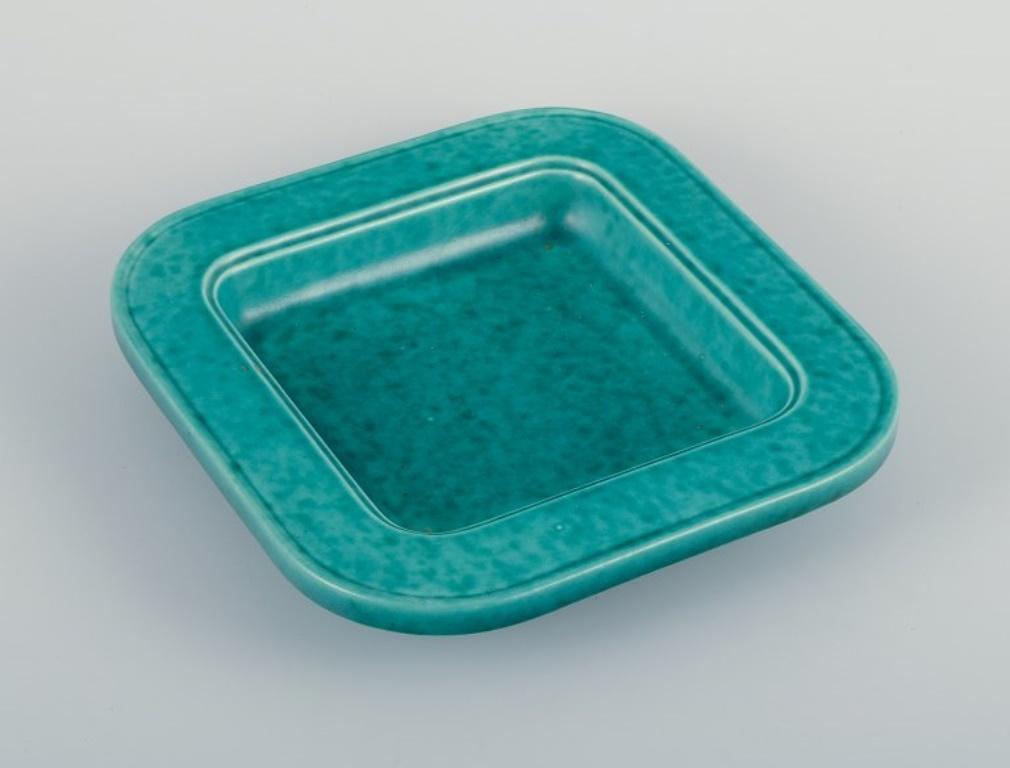 Wilhelm Kåge (1889-1960) for Gustavsberg.
Square ceramic bowl.
Classic green glaze from the Argenta series.
Mid-20th century.
In perfect condition.
Unmarked.
Dimensions: D 21.0 cm x H 4.0 cm.

Wilhelm Kåge is a prominent figure in the esteemed