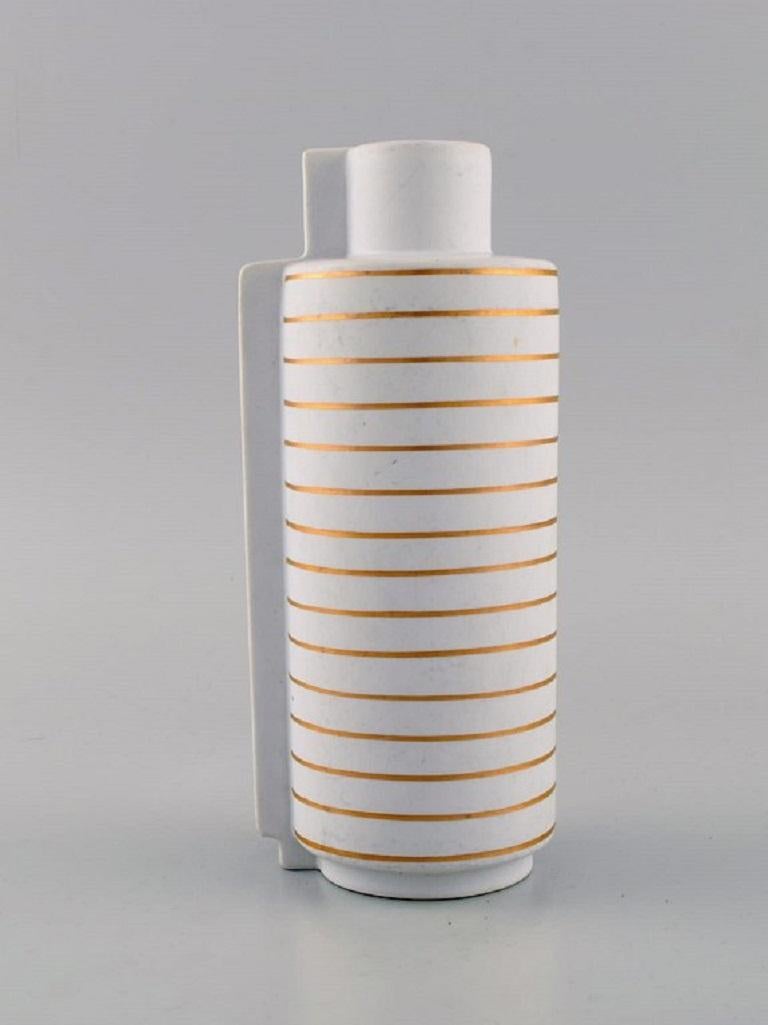 Wilhelm Kåge for Gustavsberg Studio hand. Gold Surrea ceramic split vase in white carrara glaze with horizontal and vertical gold stripes. 
Iconic and surreal design. The Surrea series was designed in 1936.
In excellent