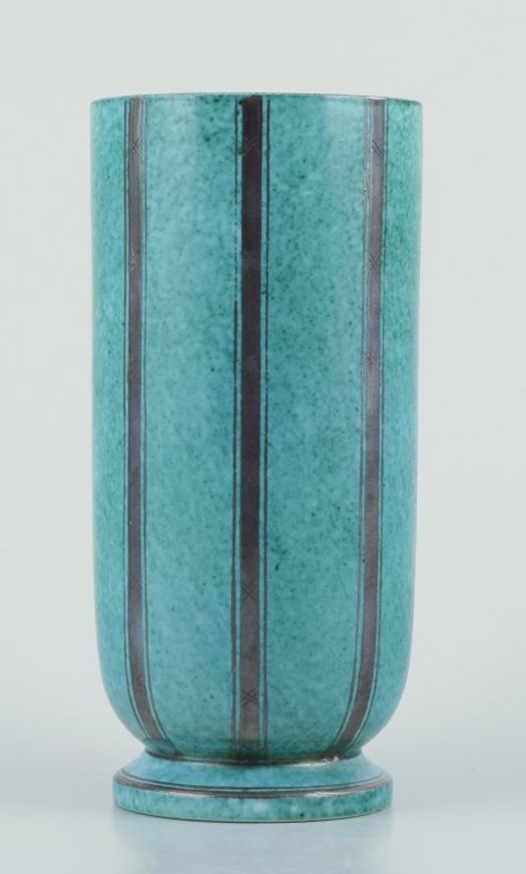 Wilhelm Kåge for Gustavsberg, Sweden.
‘Argenta’ ceramic vase. With silver decoration.
Art Deco style.
Hand-turned.
Model number 1115
Circa 1940s.
Marked.
In excellent condition with minimal signs of use.
Dimensions: H 18.0 cm. x D 8.5 cm.