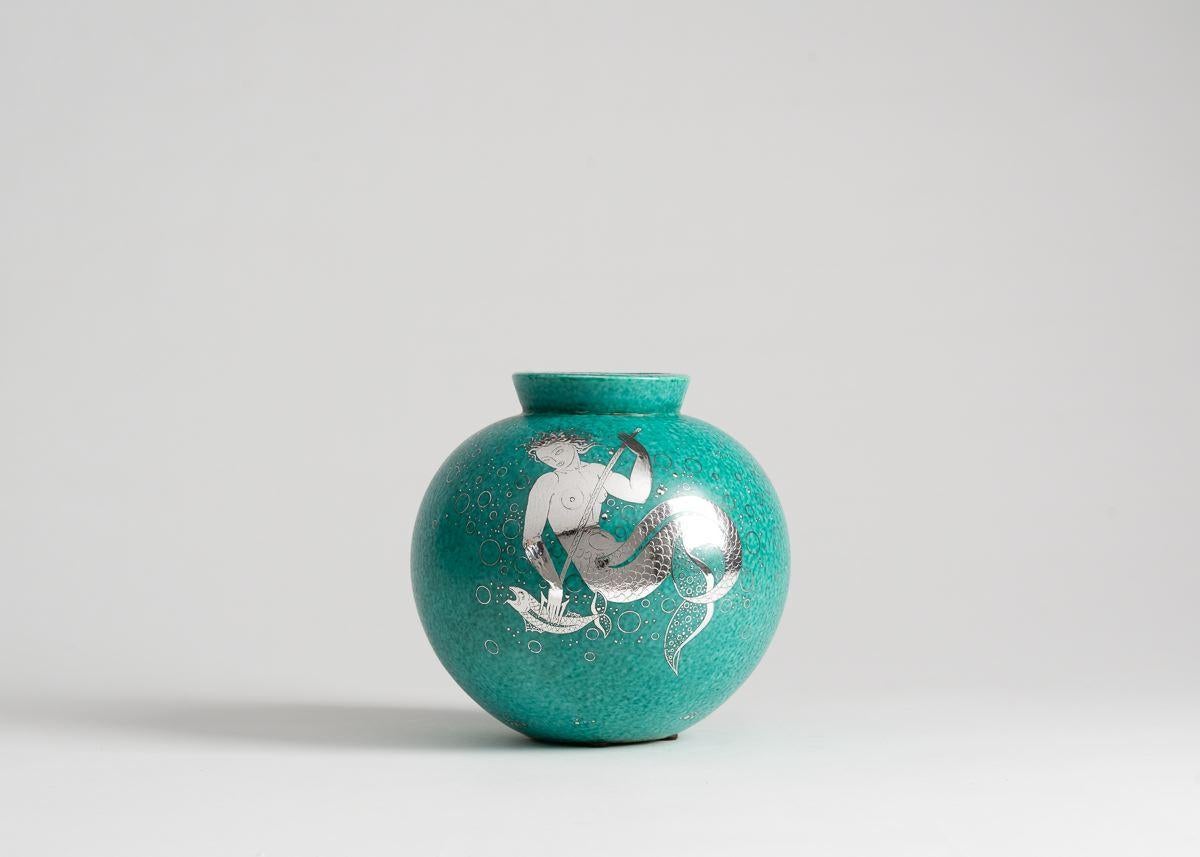 This beautiful piece is part of the artist's Argenta series, produced for the Gustavsberg Factory, which first won him major success. The series includes everything from ashtrays to 60 kg urns-- primarily in a green glaze with silver