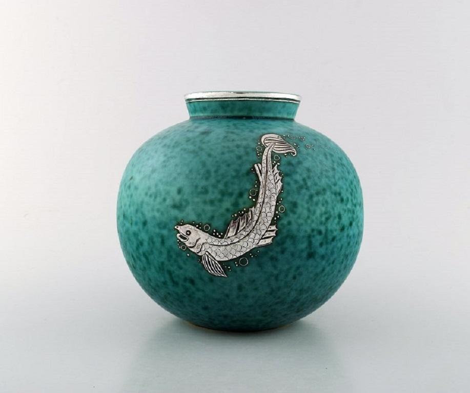 Wilhelm Kåge, Gustavsberg, Round hand-crafted Art Deco vase in ceramic decorated with fish in silver inlaid.
Sweden 1940's.
Measures: 18.5 x 17 cm.
Stamped Gustavsberg, Kåge.
In perfect condition.
