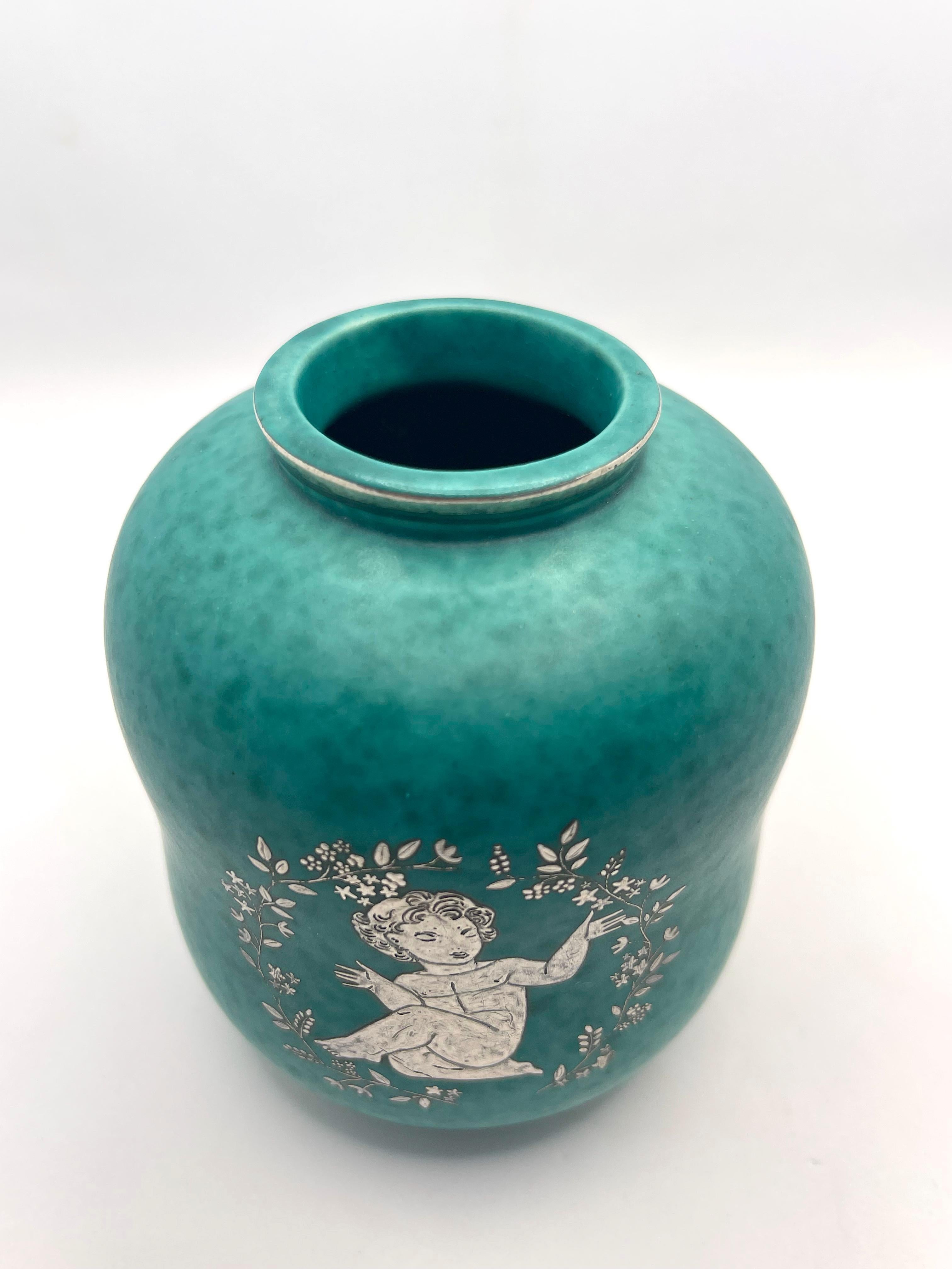 Vase by Wilhelm Kage made by Gustavsberg in Sweden around 1950 figuring silver inlay figuring an angel with stylised flower. Signed GUSTAVSBERG ARGENTA with anchor 1079
Good condition

Wilhelm Kåge (1889-1960) is one of the most well-known