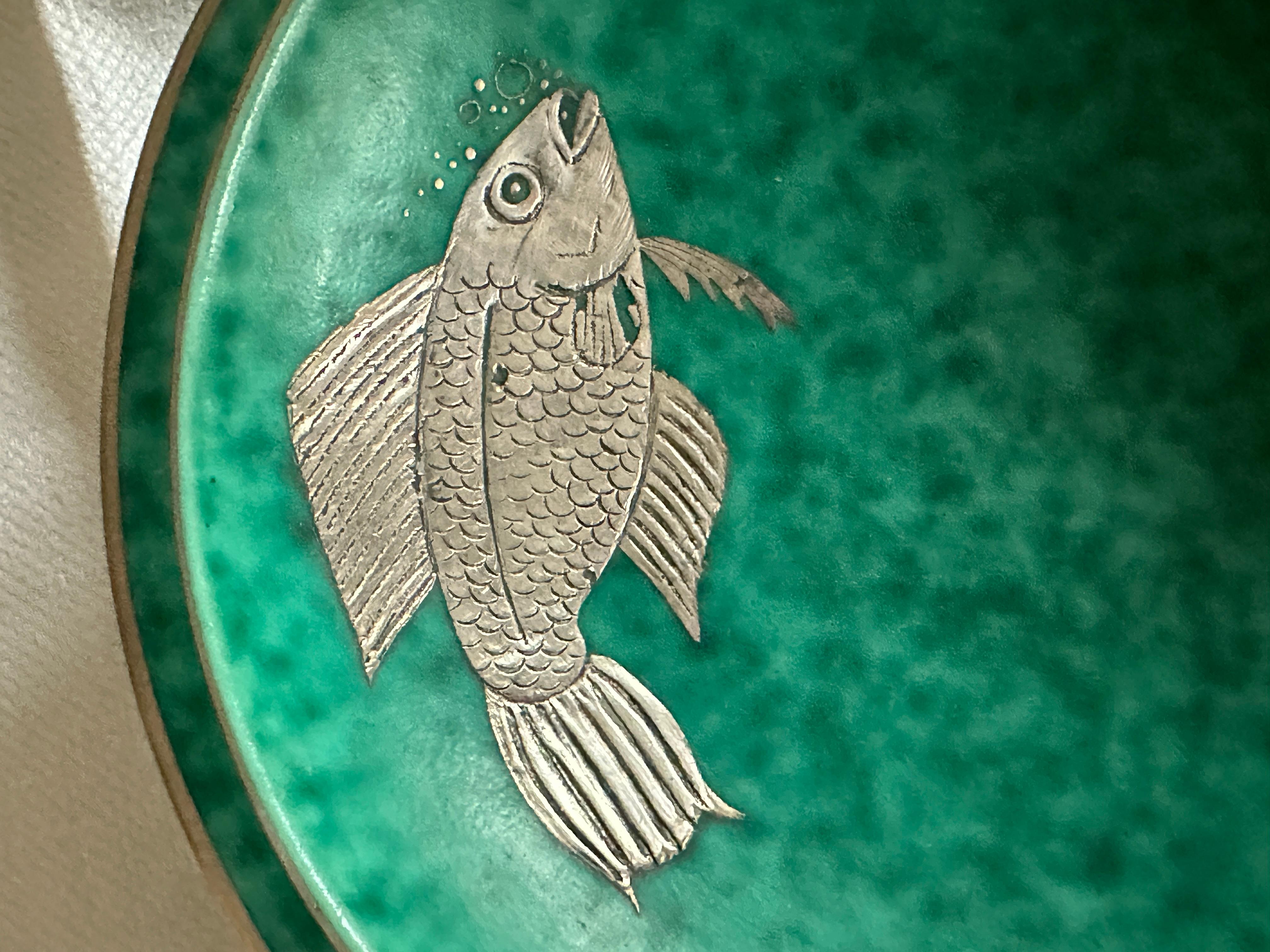 Schöne Schale mit Silbereinlage, die einen Fisch und Blasen darstellt... Argenta série von Wilhelm kage, Gustavsberg.
Guter Zustand
Wilhelm Kåge (1889-1960) ist einer der bekanntesten Vertreter des berühmten schwedischen Keramikdesigns des 20.