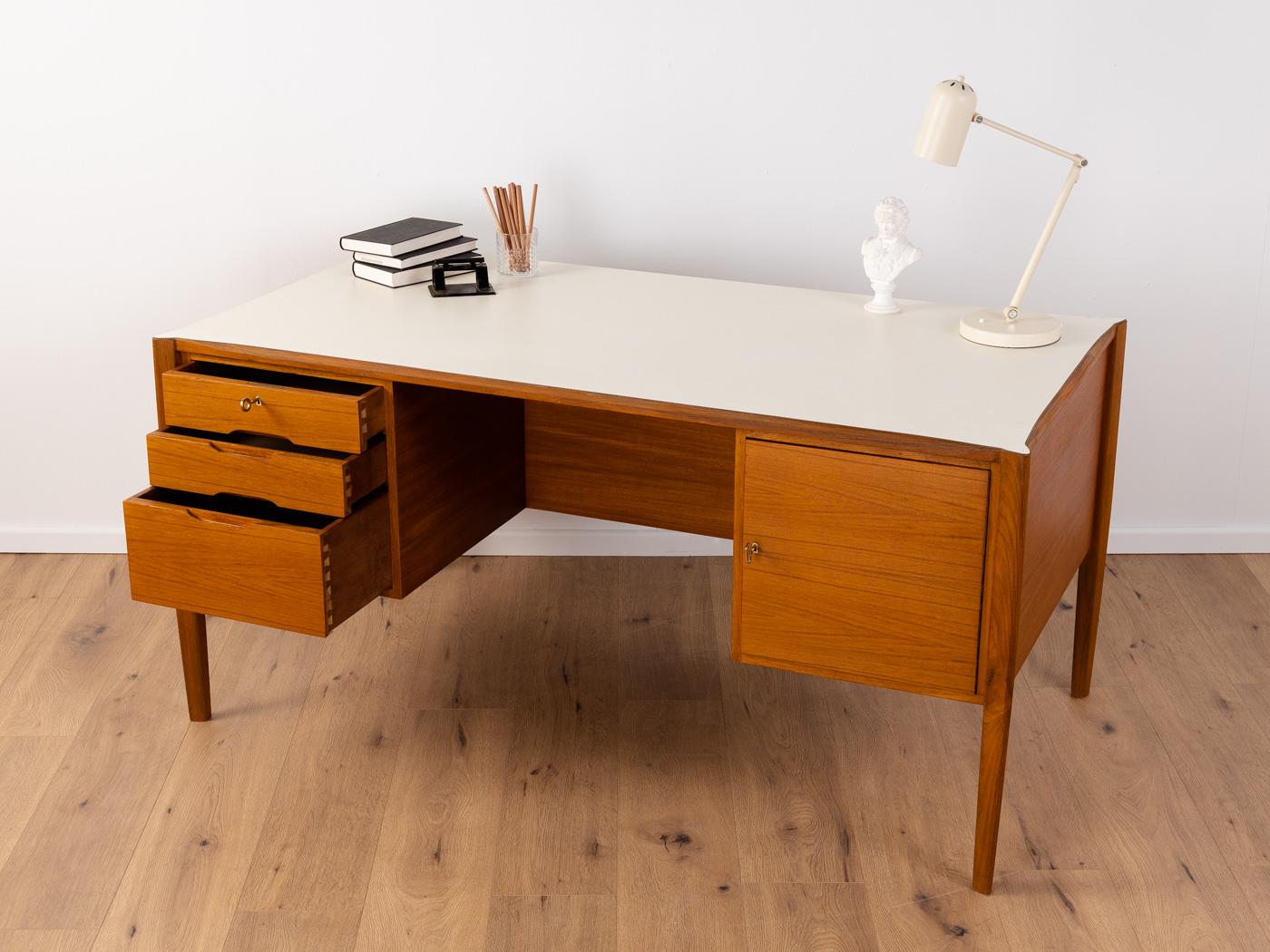 Wonderful freestanding desk from the 1960s. High-quality corpus in teak veneer with three drawers, one door, a book compartment on the rear and tapered feet. The top is coated with creamy white Formica.
Table bottom edge 63 cm

Quality