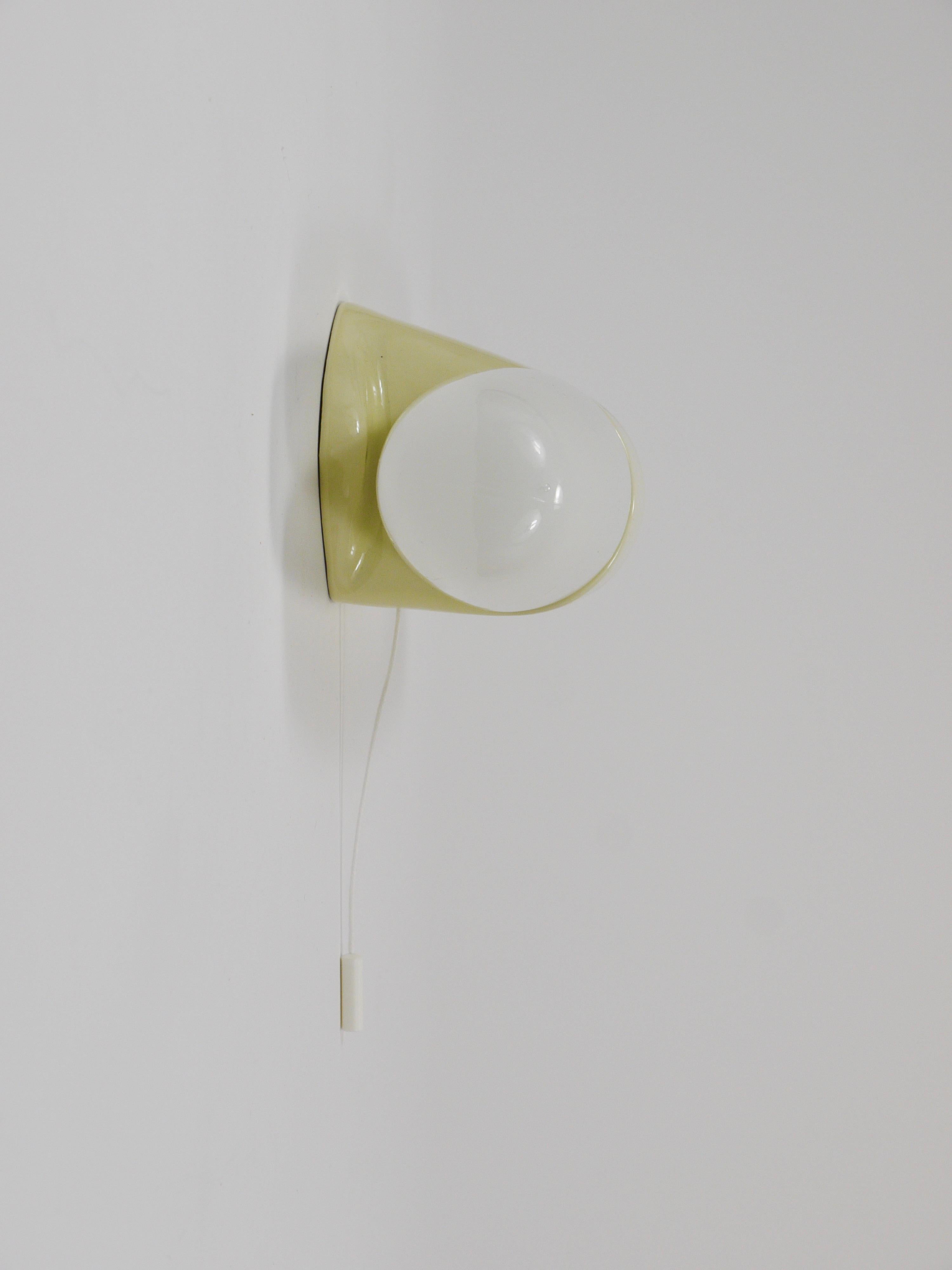 Aplique/plafón de pared de doble casquillo de la Modernidad de mediados de siglo, de la década de 1950, diseñado por Wilhelm Wagenfeld. Su forma se asemeja a la de un zepelín o un puro, está fabricada en porcelana con esmalte amarillo pastel claro y