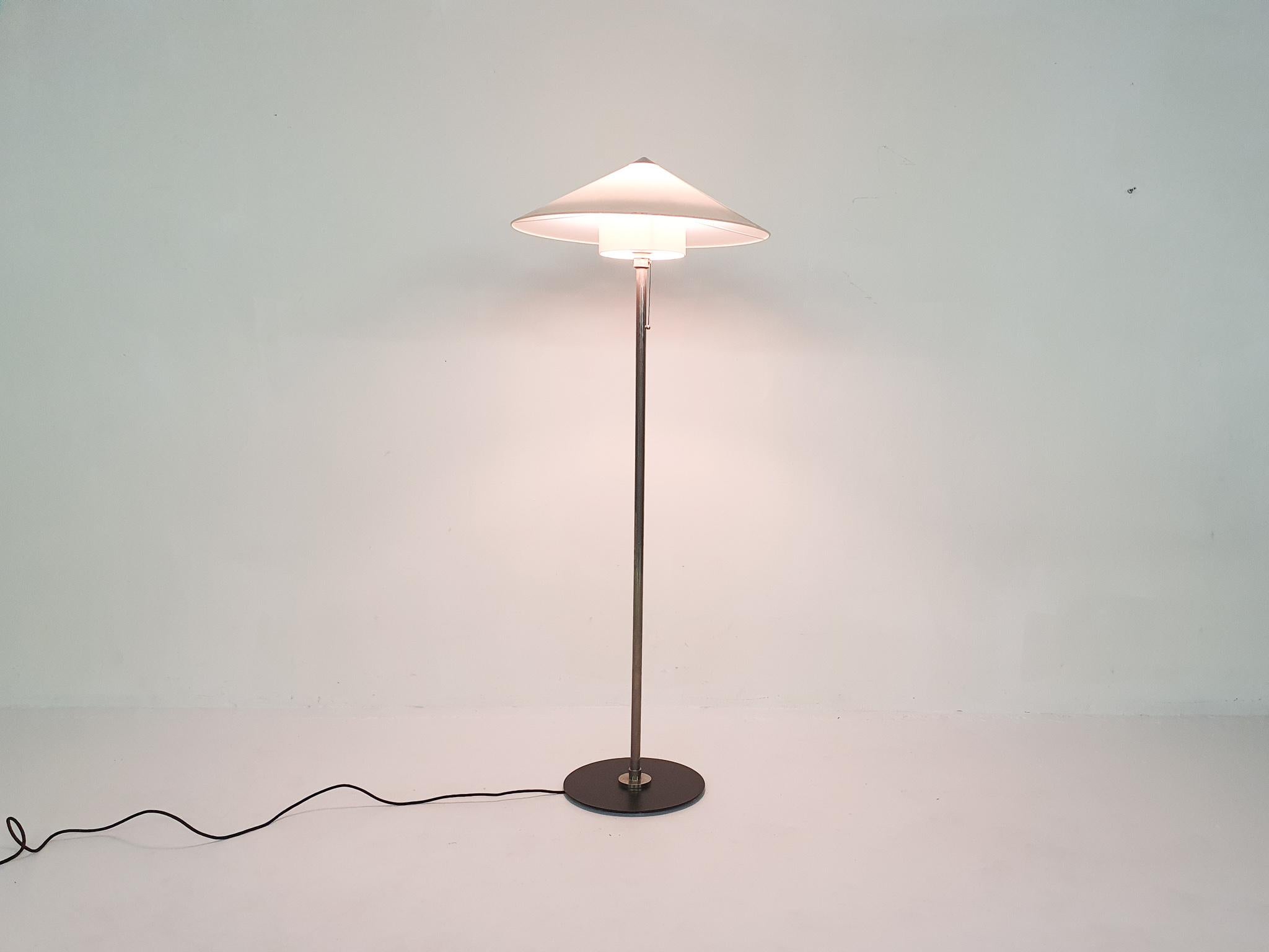 Metal floor lamp with synthetic lamp shade. 
The design is from 1930 but this is a newer edition with EU plug. Marked with Tecnolumen sticker.
Some small stains on the edge of he lamp shade and on the inner shade.