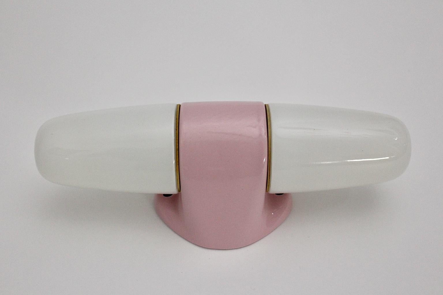A Wilhelm Wagenfeld Mid-Century Modern vintage pink ceramic glass sconce or wall light, which was designed by Wilhelm Wagenfeld and produced by Linder, Germany, circa 1950s.
The lighting shows pastel tones in pink and white, while the base was made