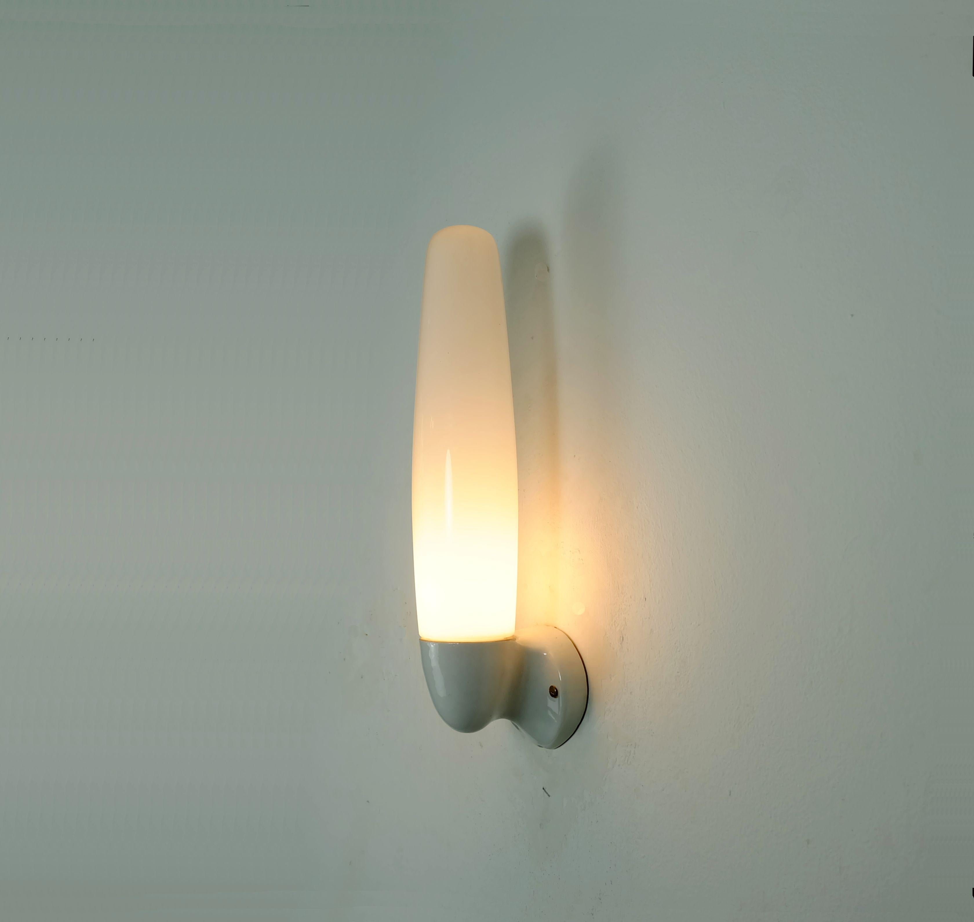German design classic: Wall lamp designed by Wilhelm Wagenfeld in 1955. Manufactured by Lindner GmbH, Bamberg, Germany. White ceramic and white opaline glass. Holds 1 E27 bulb. 

Height 16 1/2