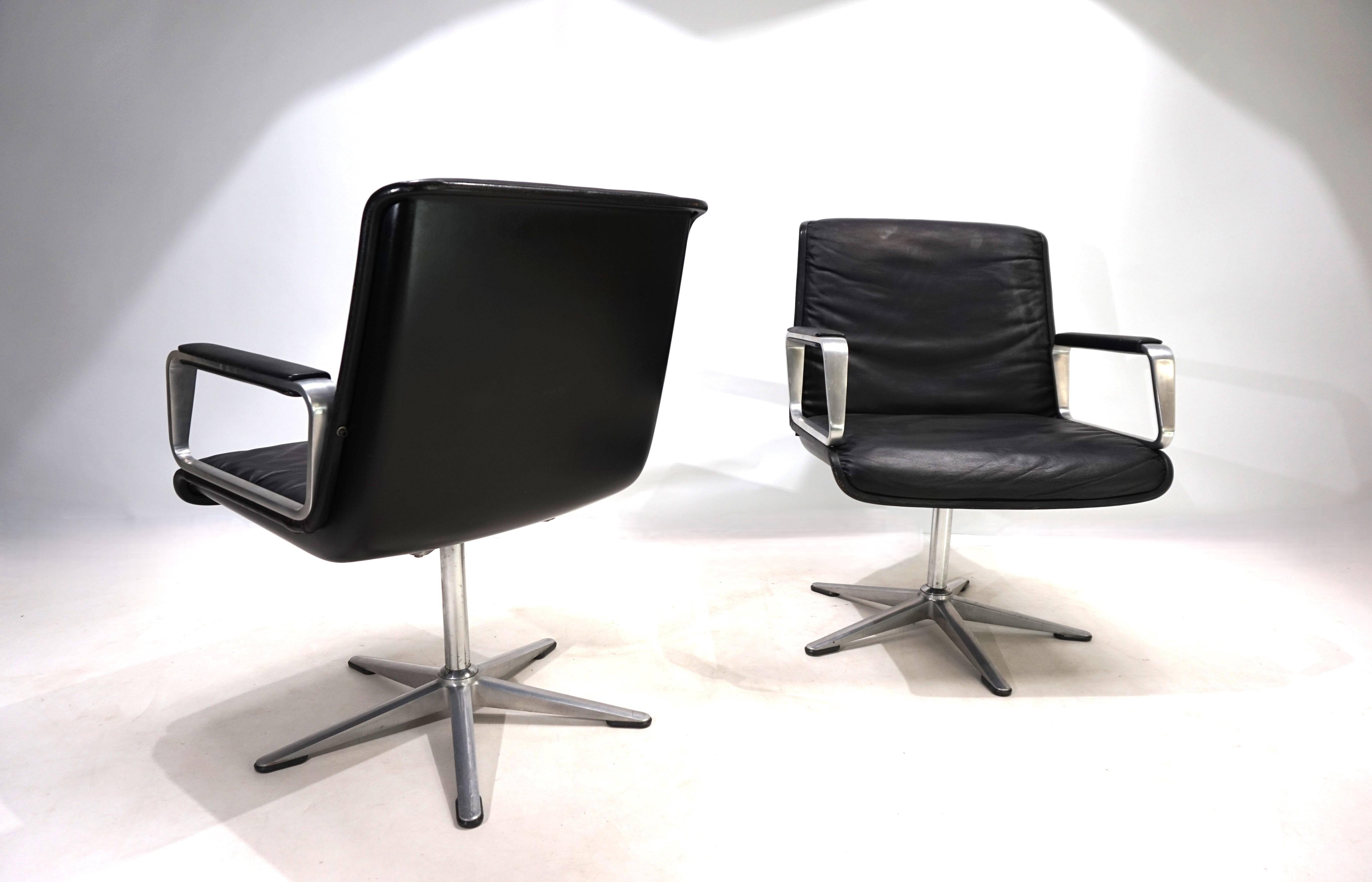 L'ensemble de deux fauteuils en cuir Wilkhahn Delta de la première génération, avec des accoudoirs en aluminium brossé recouverts de cuir et avec des coques noires, est en excellent état. Le cuir est impeccable, les coques en plastique et les pieds