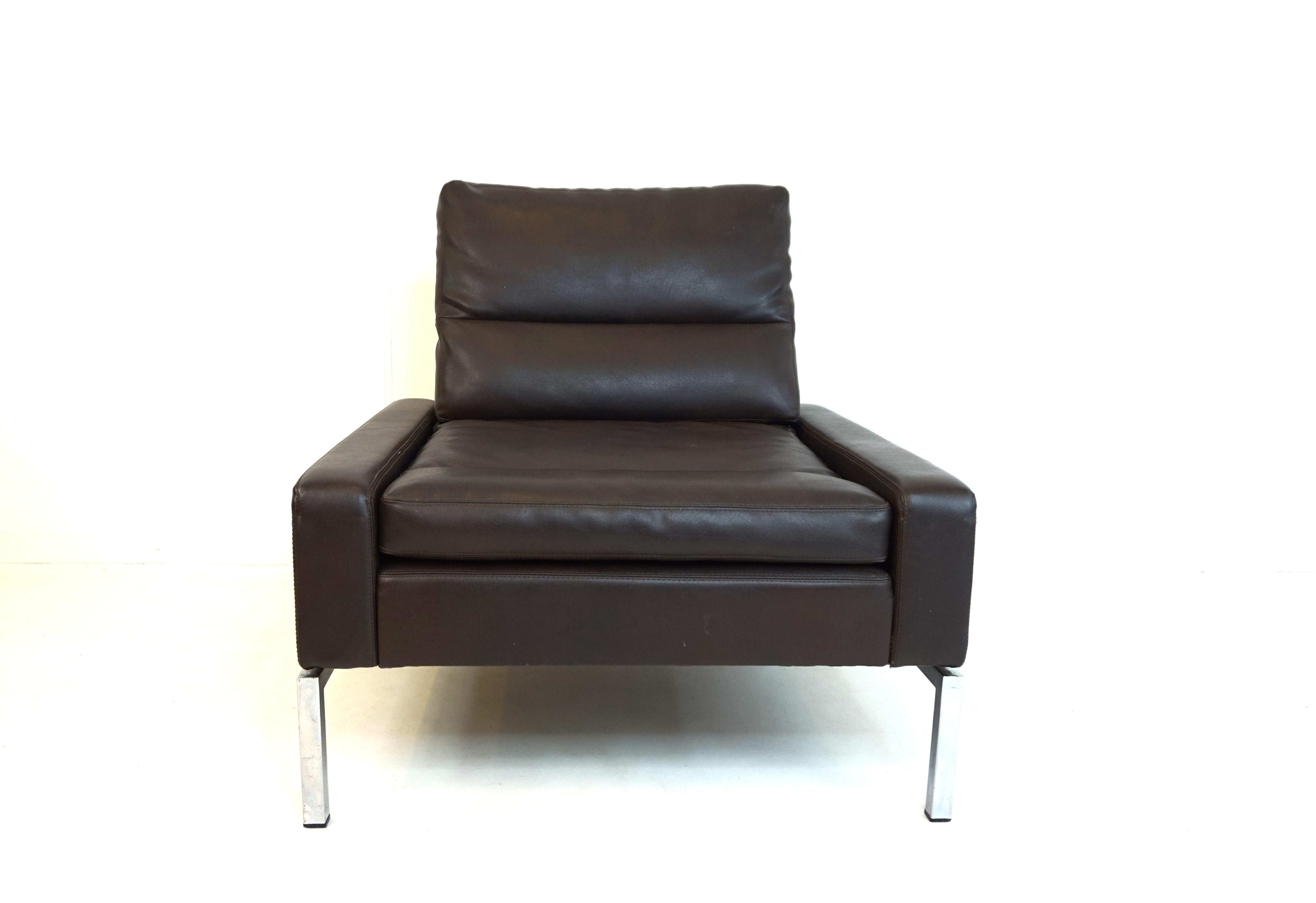 This lounge chair is upholstered in dark brown faux leather and is in excellent condition. The leather cover of the body and the cushions show hardly any signs of wear, the seating comfort is impeccable and the chrome frame is in good condition. The