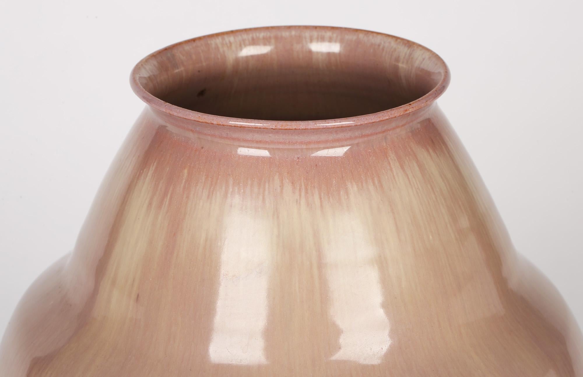 A large and attractive Dutch Art Deco vase decorated in pink streaked glazes by Willem Brouwer and made between 1920 and 1930. The vase is made in terracotta clay and is of rounded bulbous shape with an angled and shaped funnel top with a narrow