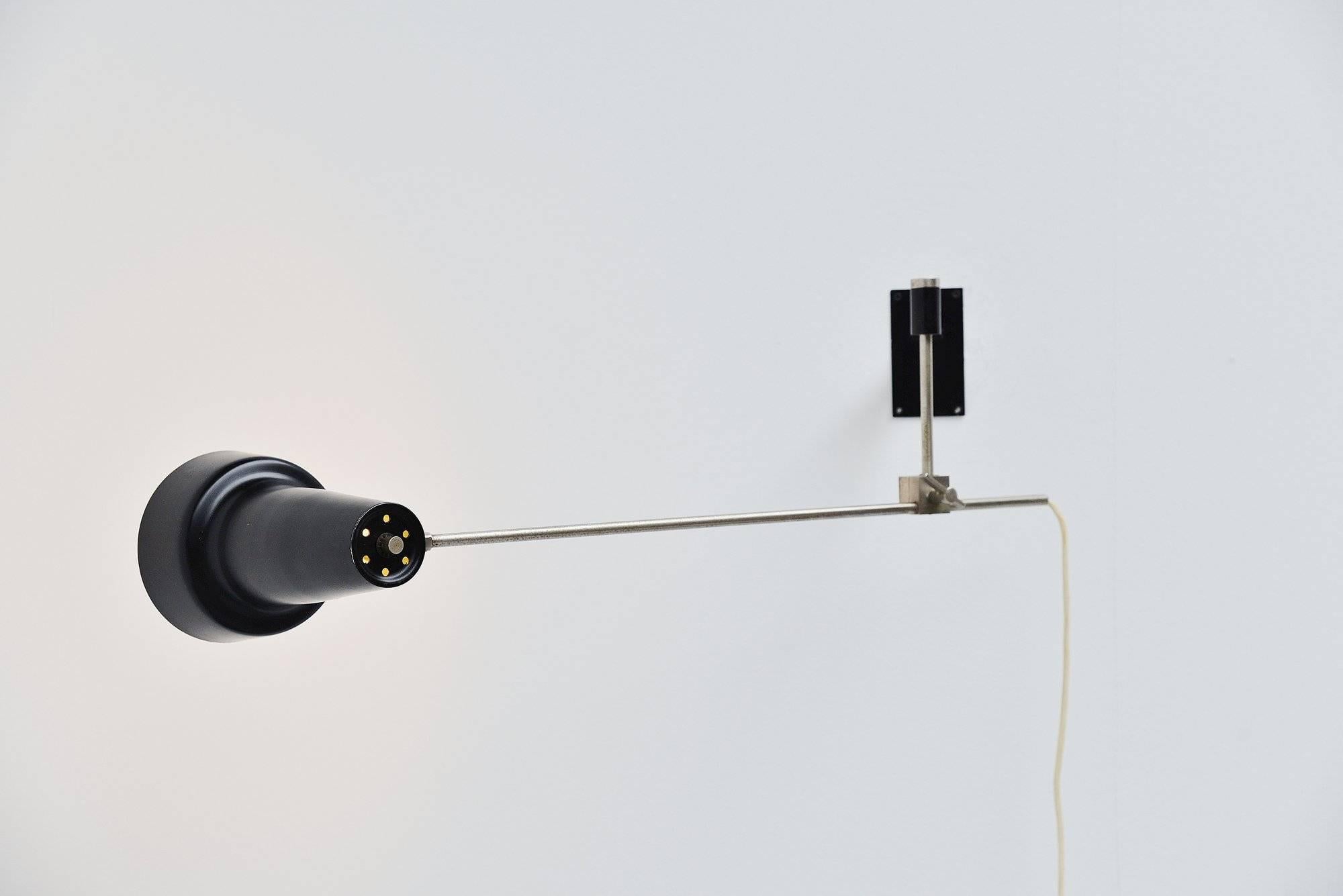 Fantastic modernist adjustable wall lamp designed and manufactured by Willem Hagoort, Holland, 1950. This unusual shaped lamp has a matt chrome plated arm and black painted shade and wall plate. The nickel plated arm has wear from age and usage but