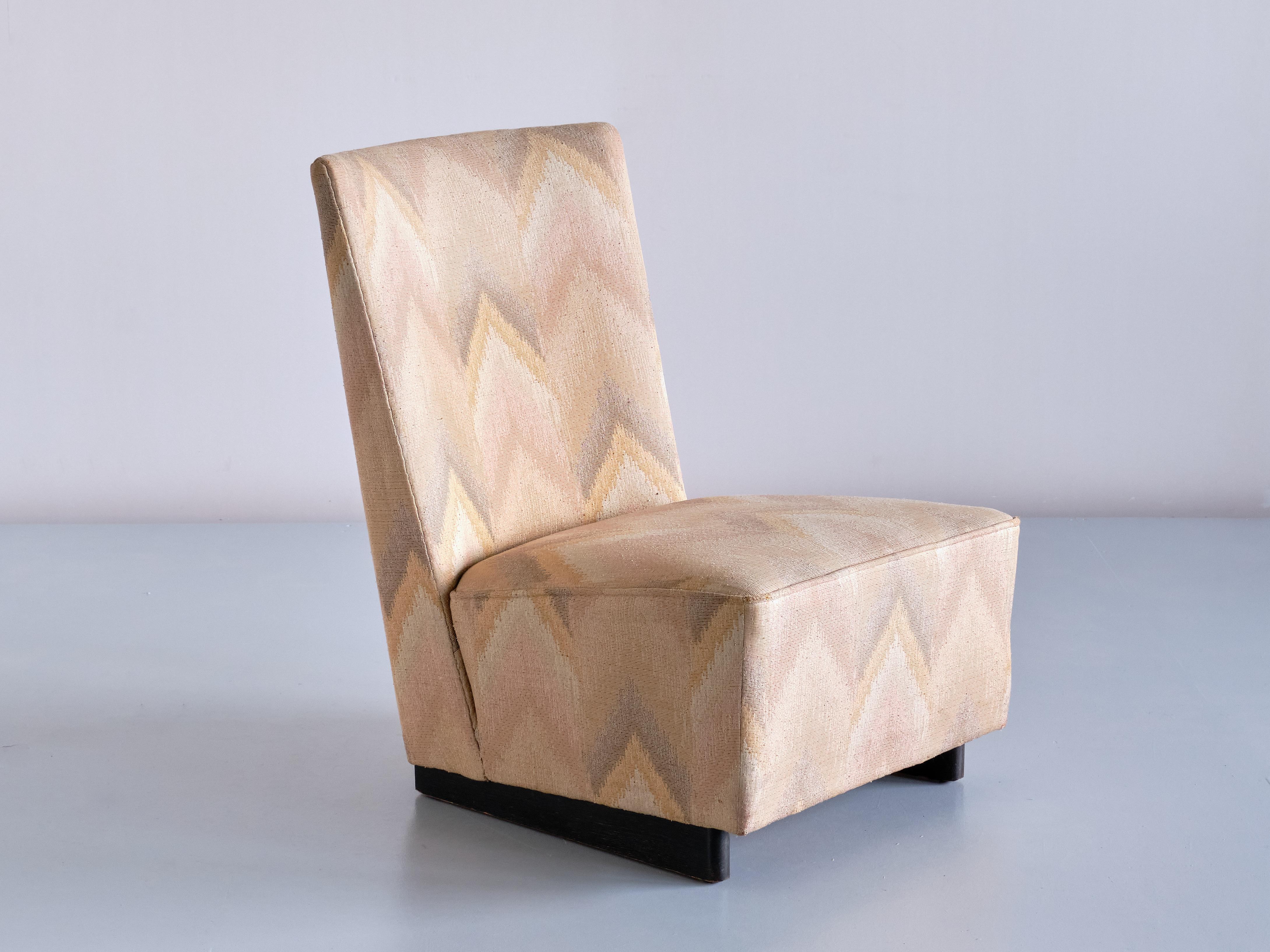 This striking low lounge or slipper chair was designed by Willem Penaat and manufactured by Metz & Co in Amsterdam in 1935. The modernist design is marked by the angled backrest and geometric shape. The chair retains its original fabric, printed in