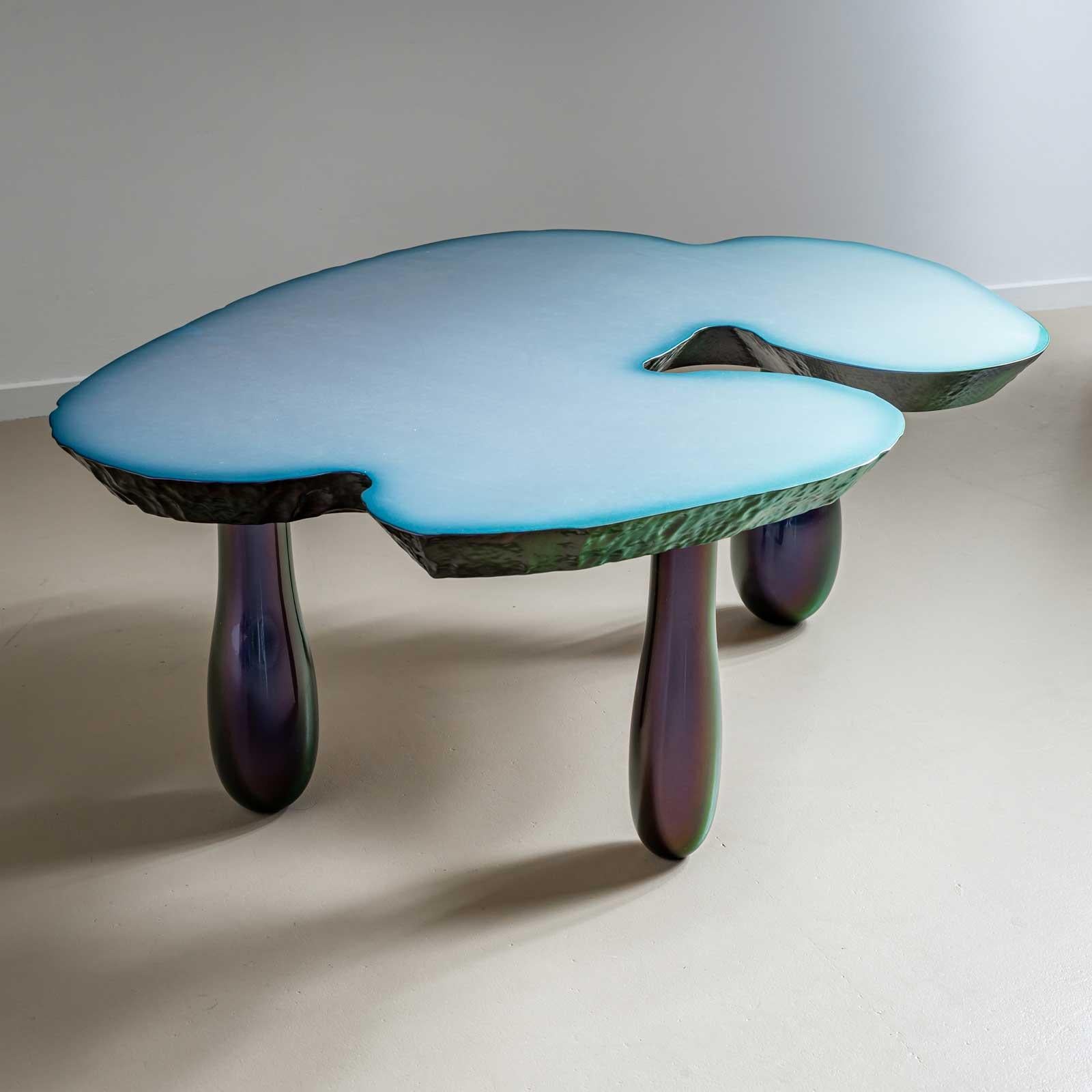 Objet de table de l'artiste allemand Willi Siber. La table repose sur trois pieds coniques de couleur vert pourpre et possède un plateau épais de forme irrégulière dont la surface est lisse et dont le bord ressemble à un paysage lunaire.

Siber