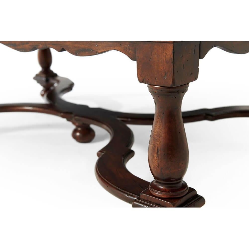 A William and Mary style antiqued mahogany wood cocktail table, with two end drawers, on turned legs joined by an 