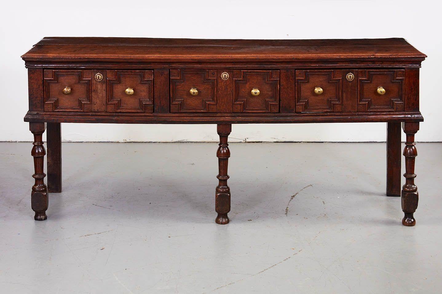 Fine English late 17th Century oak low dresser, the two plank top with beveled edge over three drawers with geometric molded fronts, on three nicely turned front legs and two plain square rear legs, the whole possessing very good rich color and
