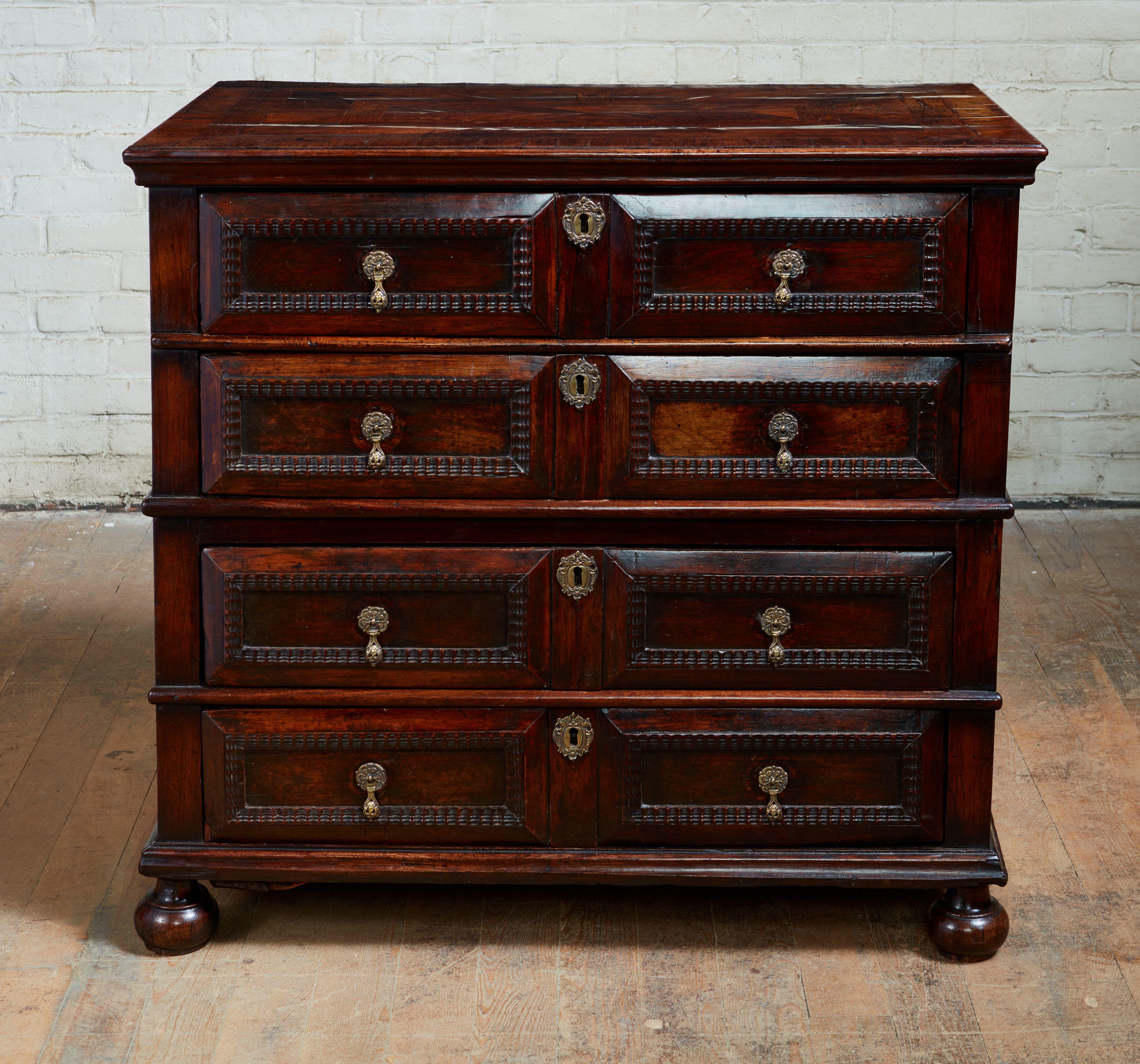 Fine and rare late 17th century English chest of drawers entirely veneered in kingwood, the parquetry top over cushion molded drawers having tear drop pulls, the carcass made in two sections having molded seam and standing on original bun feet, the
