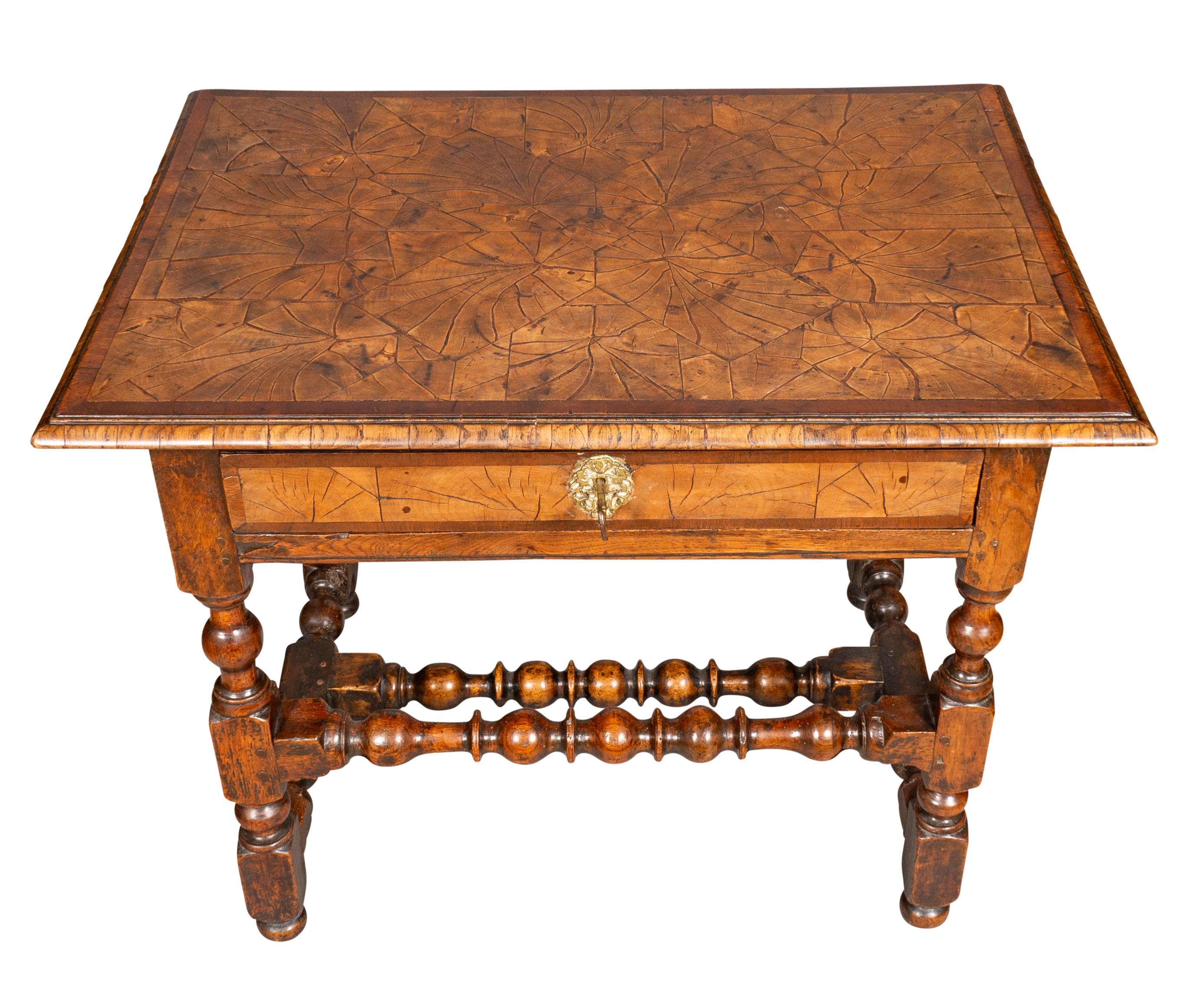 With a rectangular top with oak oyster veneer decoration. Over a drawer and raised on turned legs joined by turned stretchers. Button feet. A more unusual example with great patina.