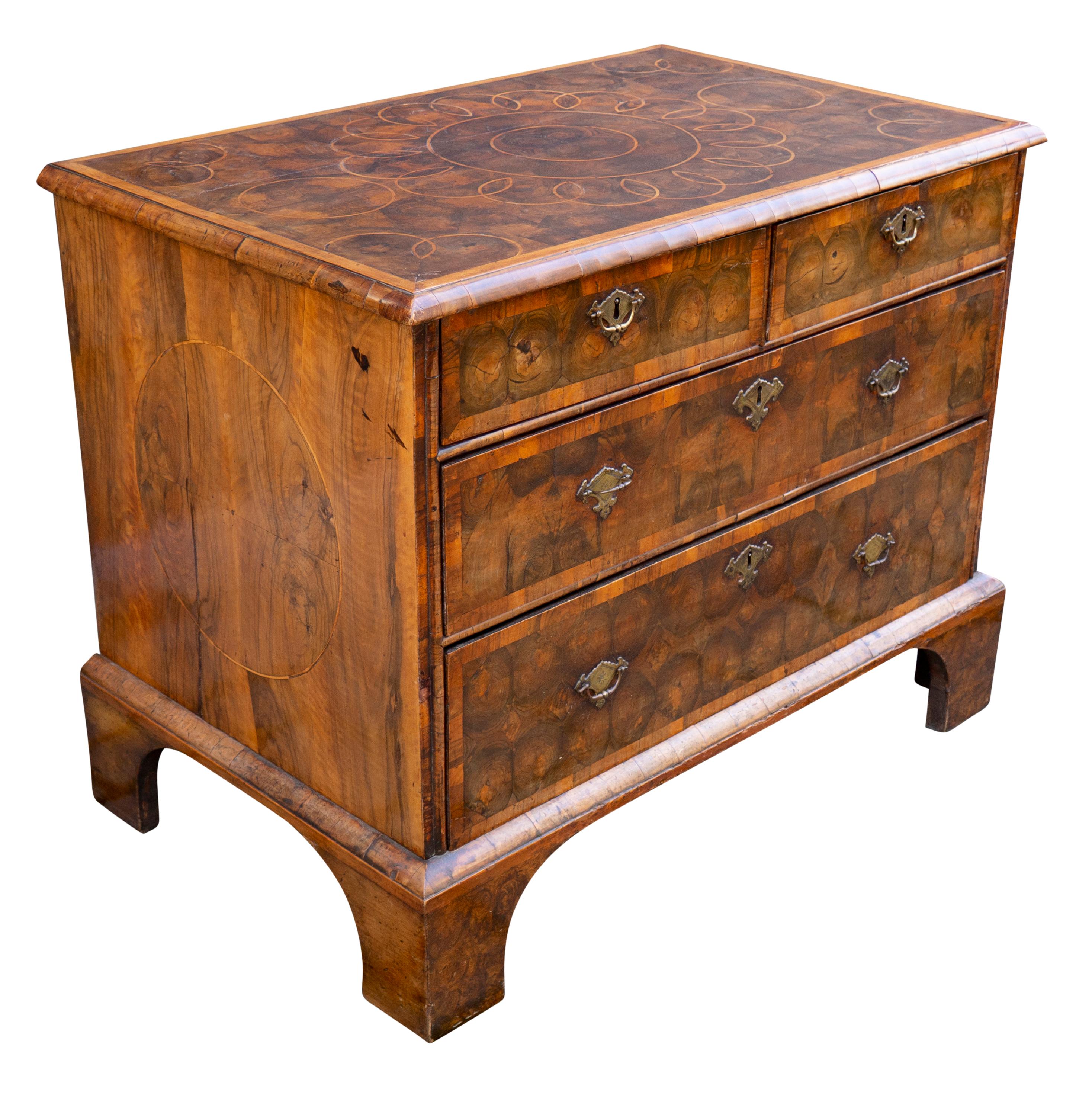 With a rectangular top with satinwood outer band and inner pattern of circles defined with boxwood stringing with overall oyster, over two over two long drawers , raised on bracket feet. Oyster veneer is created by cutting thin cross sections of a