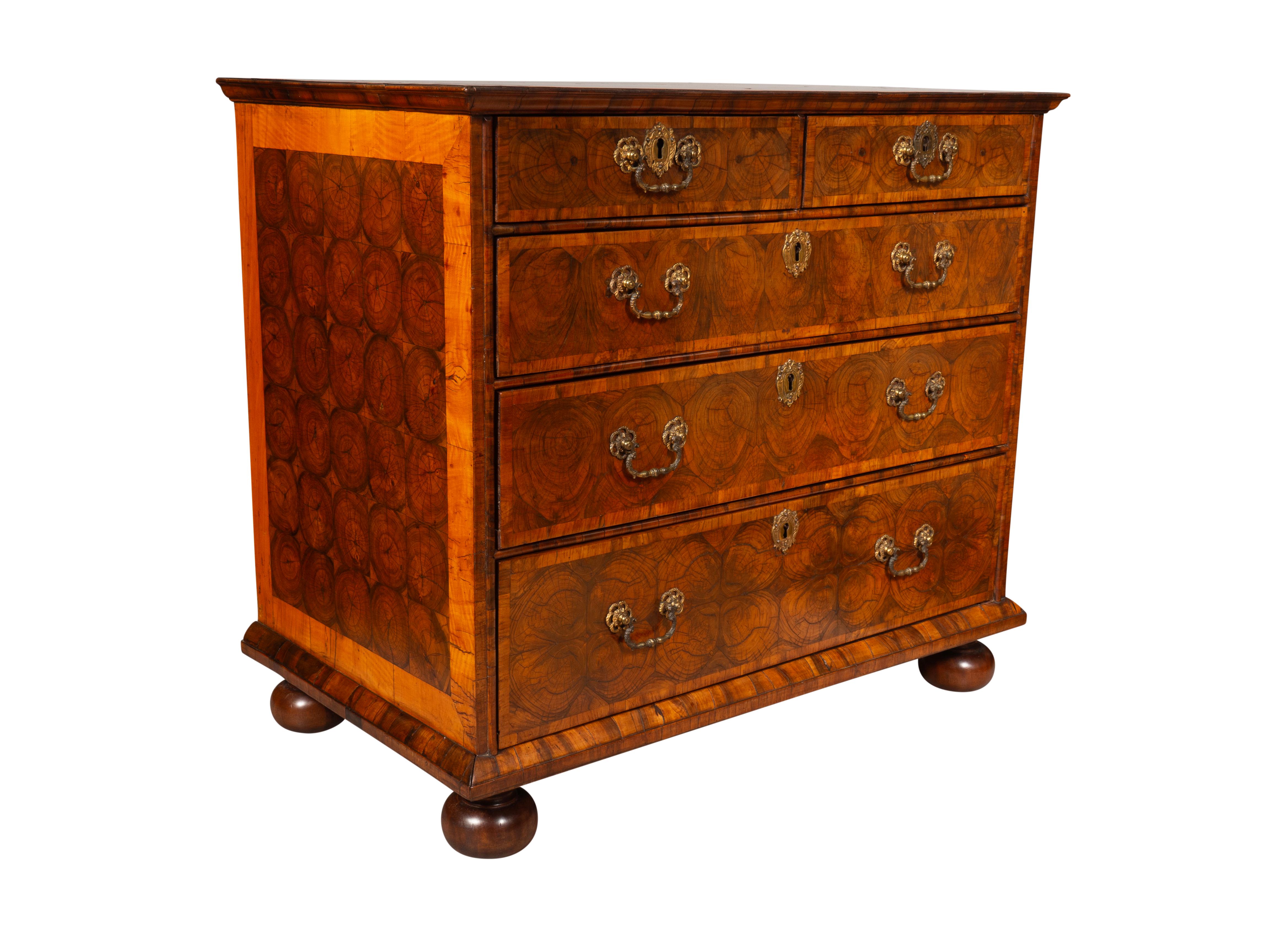 With a rectangular top with overall oyster decoration over two over three drawers with replaced but old gilt bronze handles. Sides and front with well executed oyster veneer. Raised on later bun feet. 