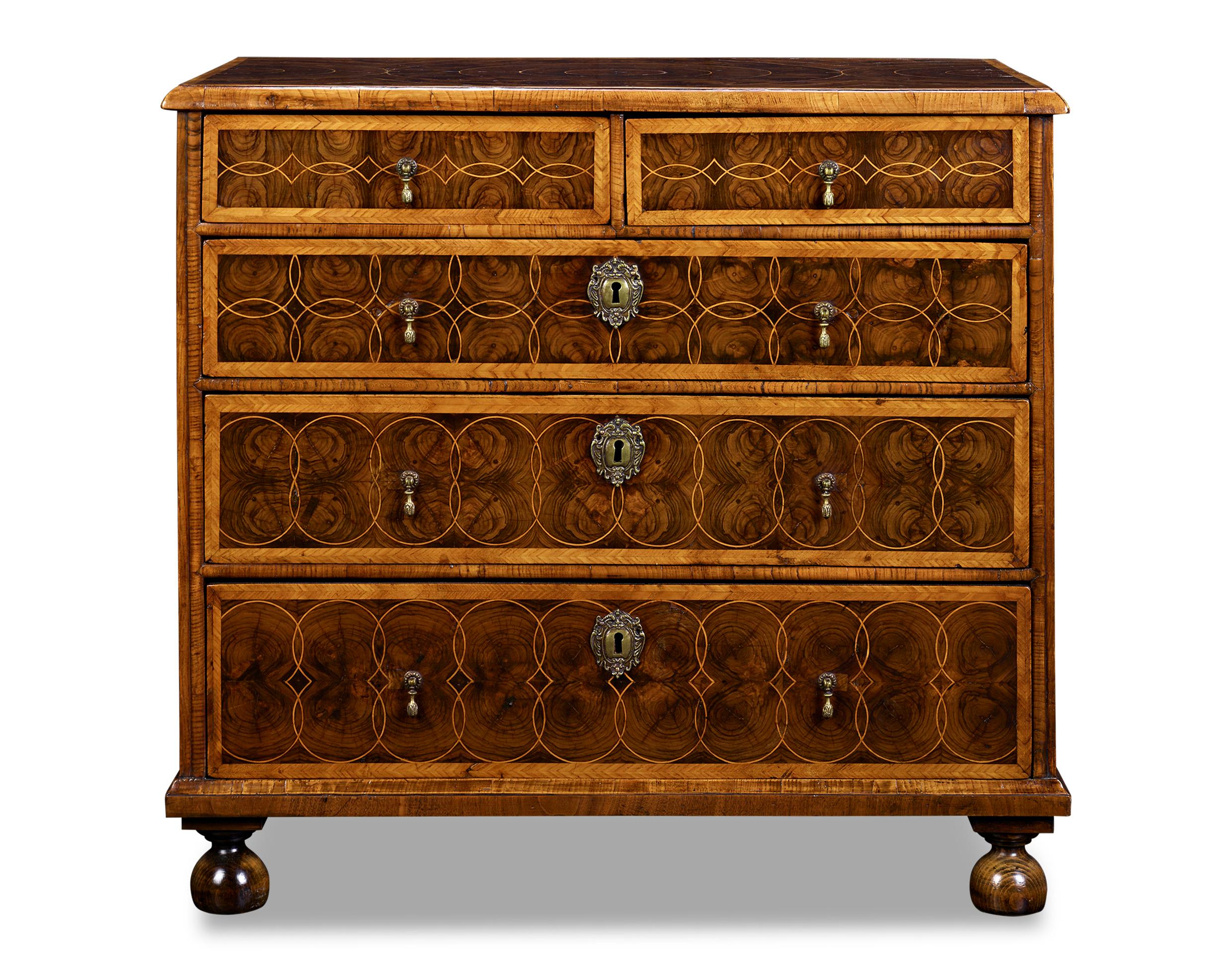This William and Mary-period chest is distinguished by oyster veneering and circular inlay. Intersecting circles are inlaid into the veneers on the drawer fronts and on top of the chest, and the veneers have aged to a rich and warm patina. The