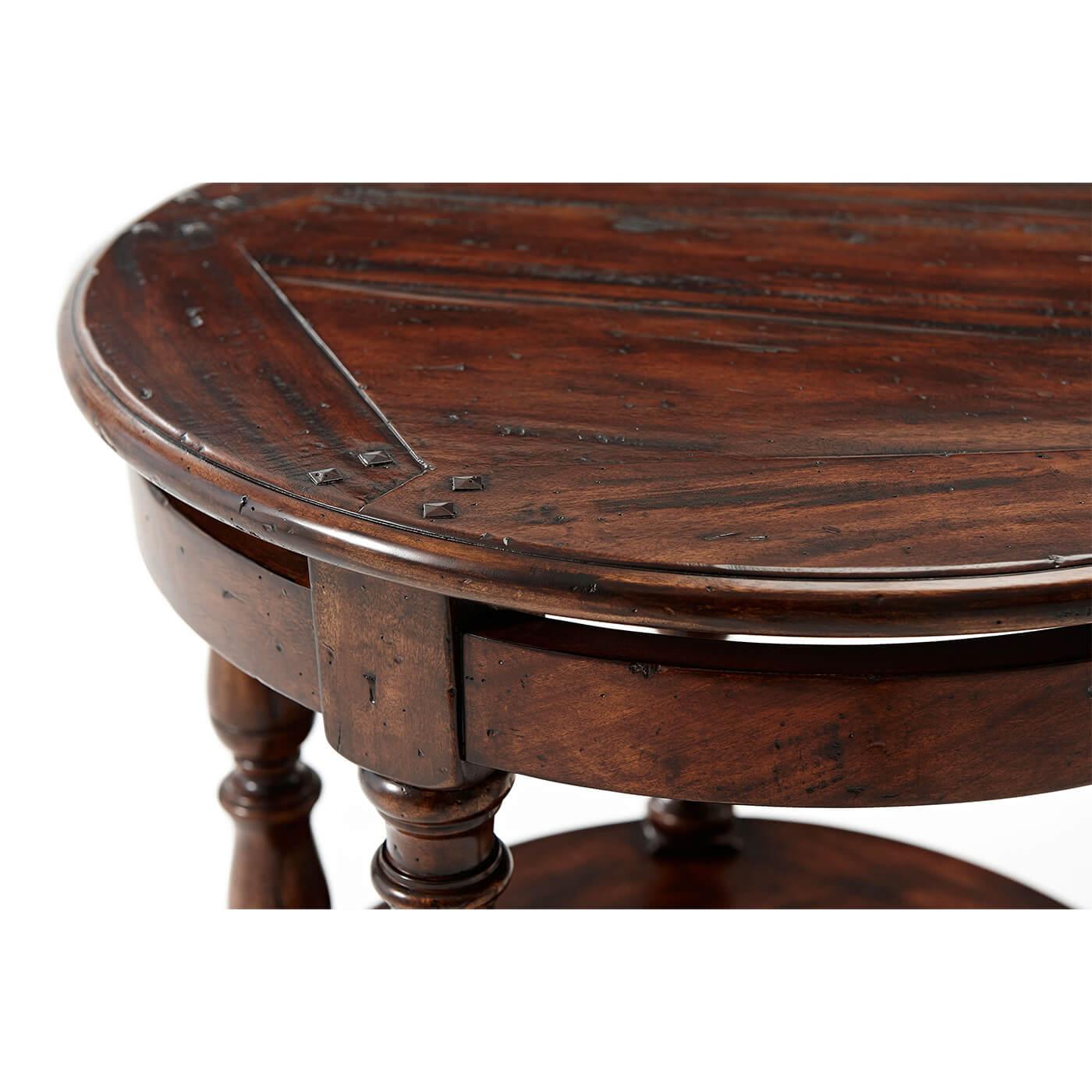 An antiqued wood lamp table, the circular top above a bowed floating frieze between turned supports joined by a planked circular under tier with a plain frieze, on turned feet. 

Dimensions: 26