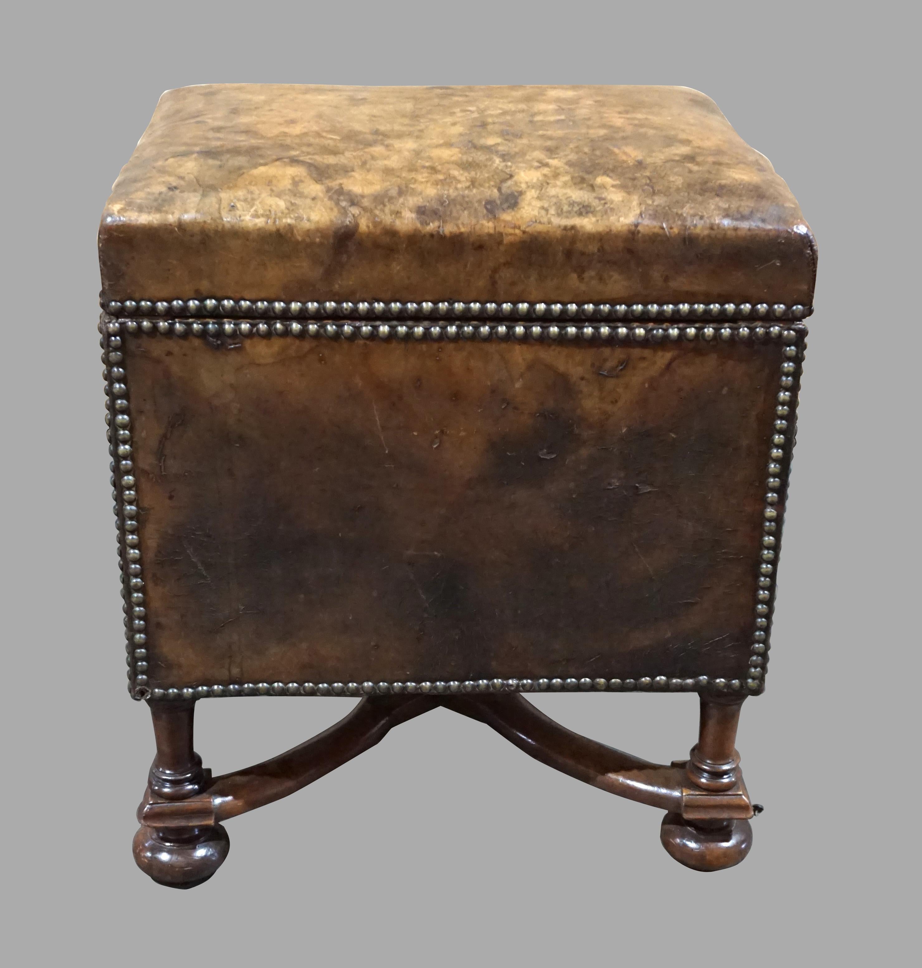 An unusual and charming walnut William and Mary style leather upholstered small trunk with nailhead trim, opening to reveal a wood lined interior, resting on a base with wavy stretcher ending in ball feet. Nineteenth century.