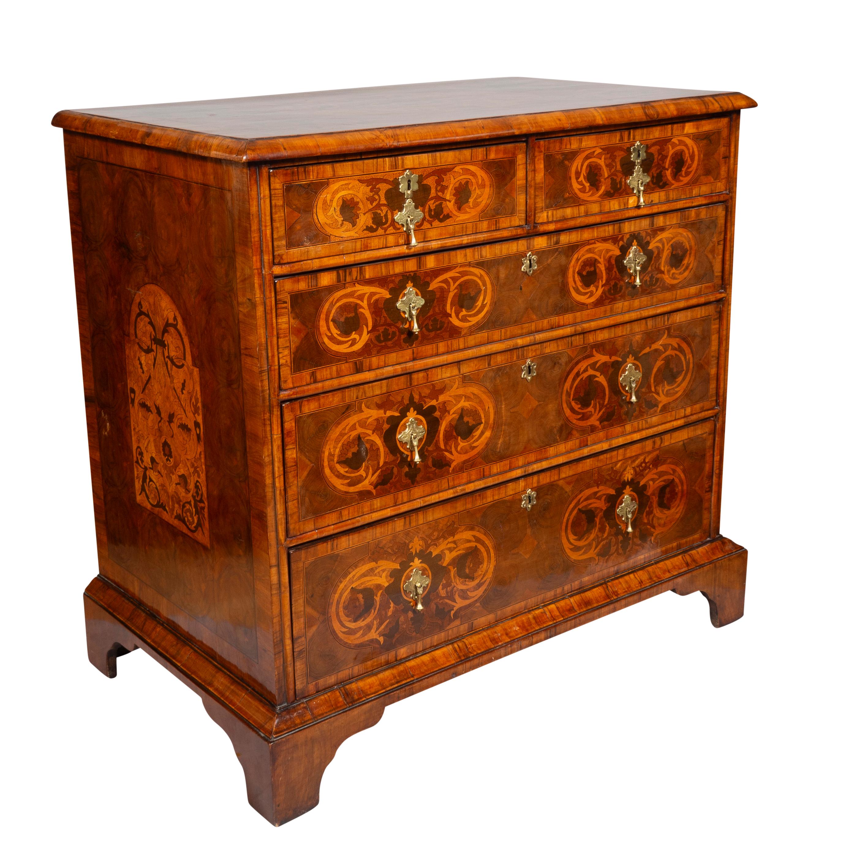 Rectangular top with central oval inlay with matching inlays at corners. Over two over three graduated drawers all with inlays complementing the top. Sides with central inlaid panels. Bracket feet. Brass tear drop handles. Provenance: Antonio's