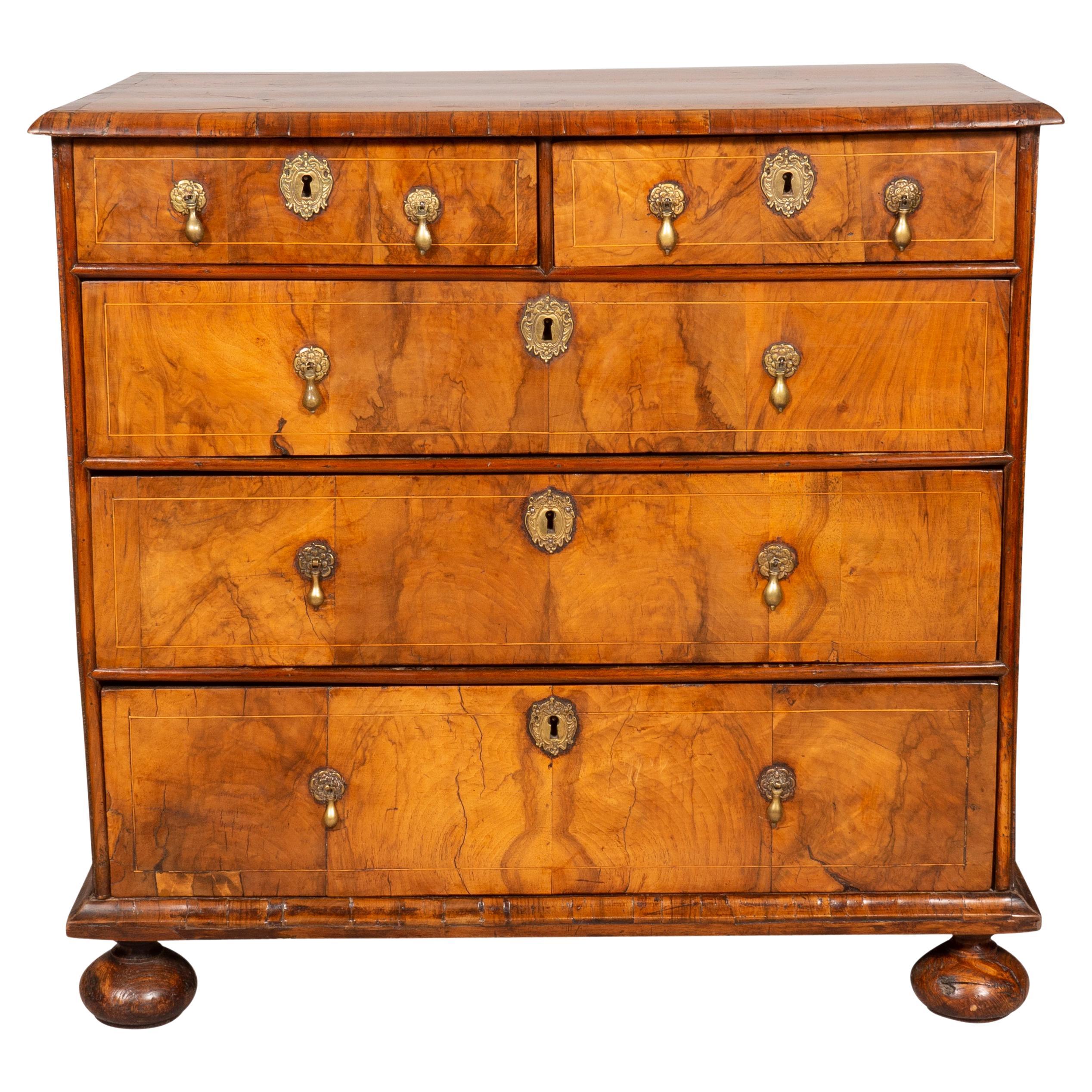 With a rectangular top with paneled inlays with central oval and spandrels over two drawers over three drawers, all with brass tear drop pulls. All terminating on bun feet. Locks and handles appear to be original. Sides are elm.